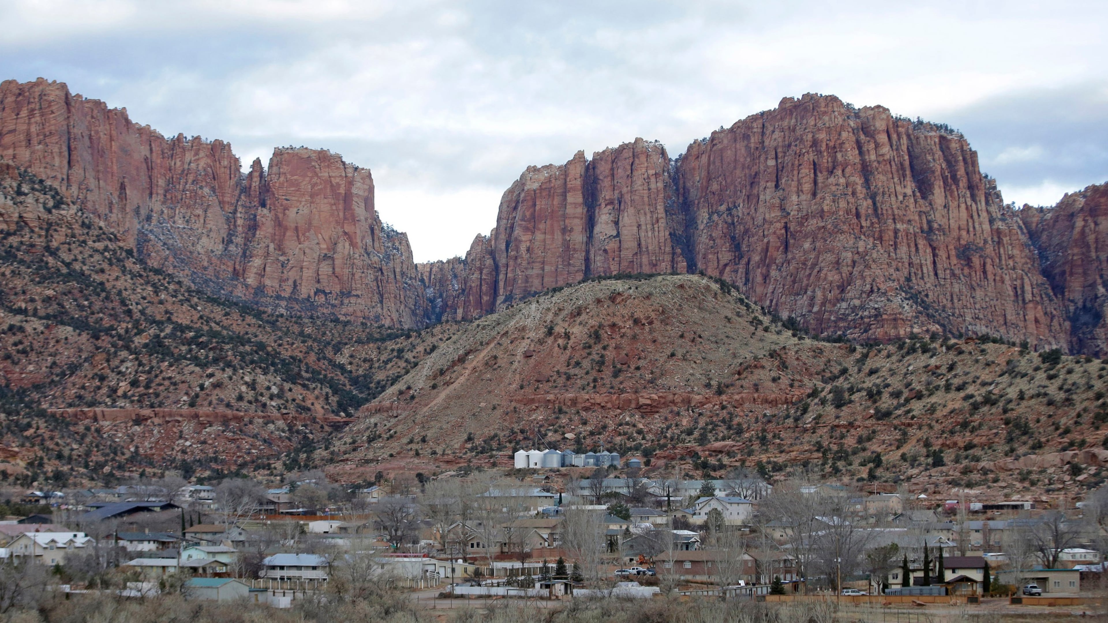 FILE - This photo shows Hildale, Utah, sitting at the base of Red Rock Cliff mountains, with its sister city, Colorado City, Ariz., in the foreground, Dec. 16, 2014. (AP Photo/Rick Bowmer, File)