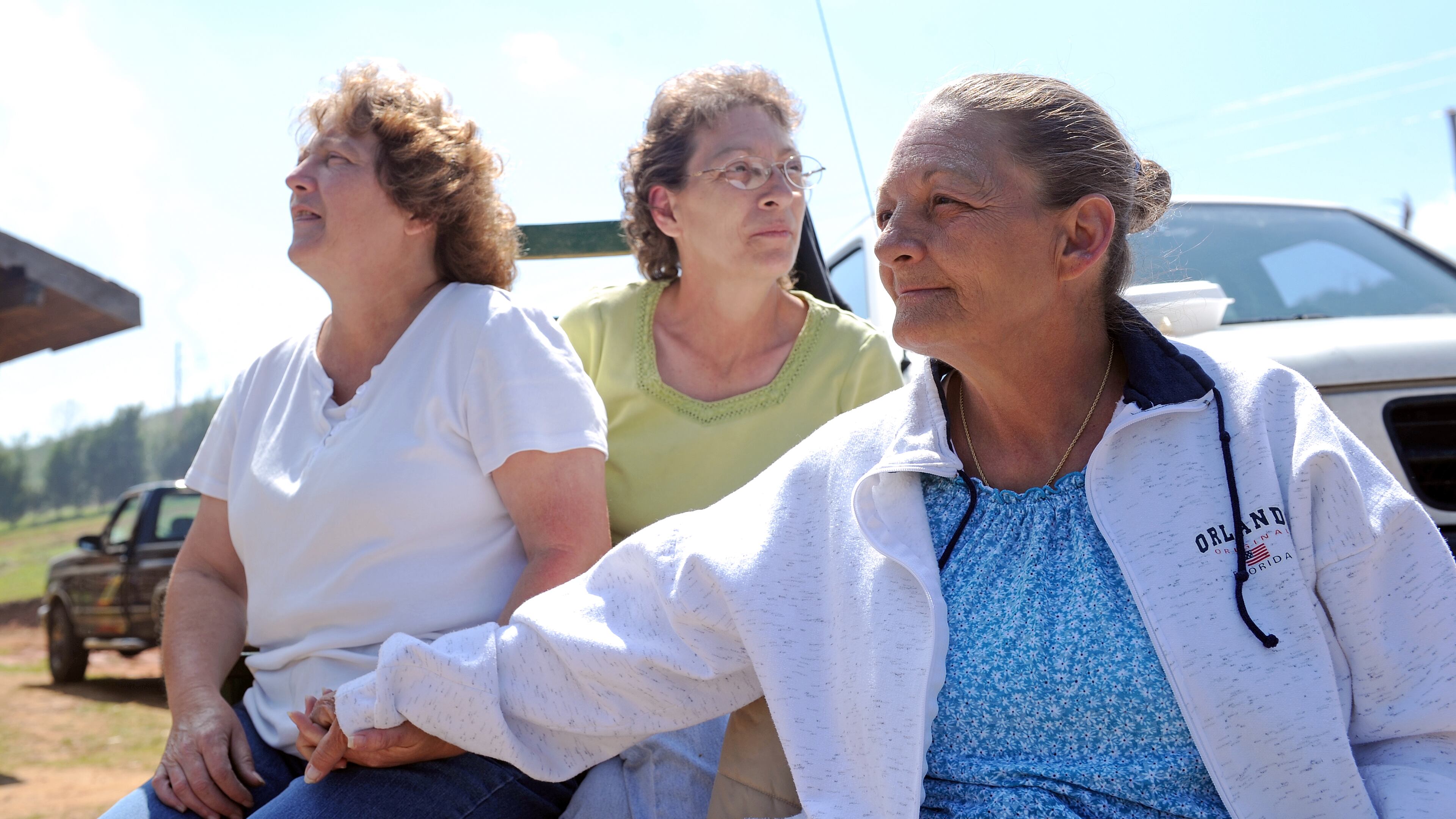 Jeanie McClure (right) sits with her sisters Karen Crider (left), and Joan Gill (center, Jeanie's twin), outside McClure's Ringgold home Wednesday, May 4, 2011. The McClure home was heavily damaged during the tornado last week and will have to be demolished and rebuilt. Volunteers and family members were helping clear debris and burn fallen timber on the property.
