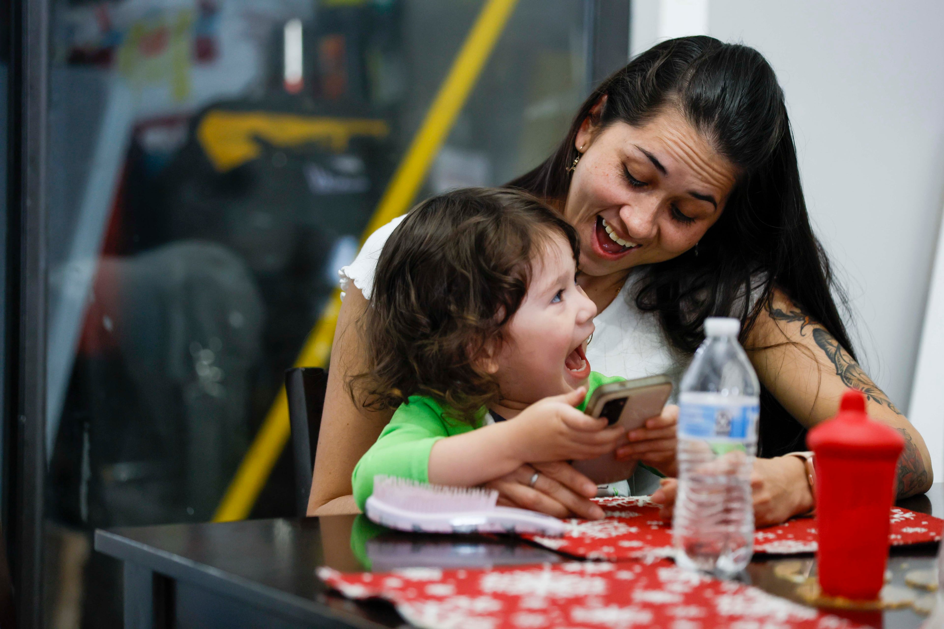 Ceudy Gutierrez shows her cell phone to her 2-year-old son, Matias, while on a call from her husband, Omar Estribi, who has been held in an immigration detention center since early September. (Miguel Martinez/ AJC)