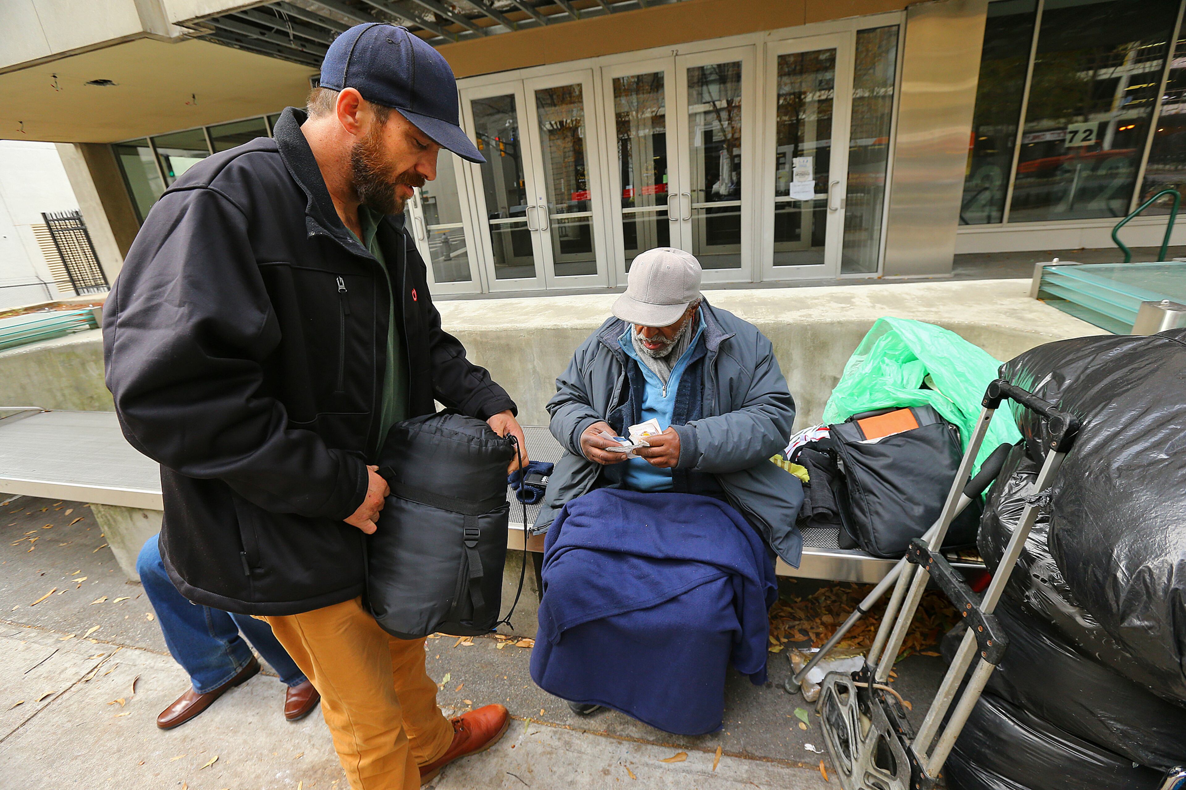 120113 ATLANTA: Joel Hartman walks the streets handing out sleeping bags to homeless men on Marietta Street on Sunday, Dec. 1, 2013, in Atlanta. Hartman, the "Homeless Hero" that returned a woman's wallet he found digging through trash hoping to find someone's leftover food, spent the morning handing out sleeping bags to the needy that were donated to him by well wishers to the Omin Hotel at CNN Center following his good deed. CURTIS COMPTON /staff CCOMPTON@AJC.COM