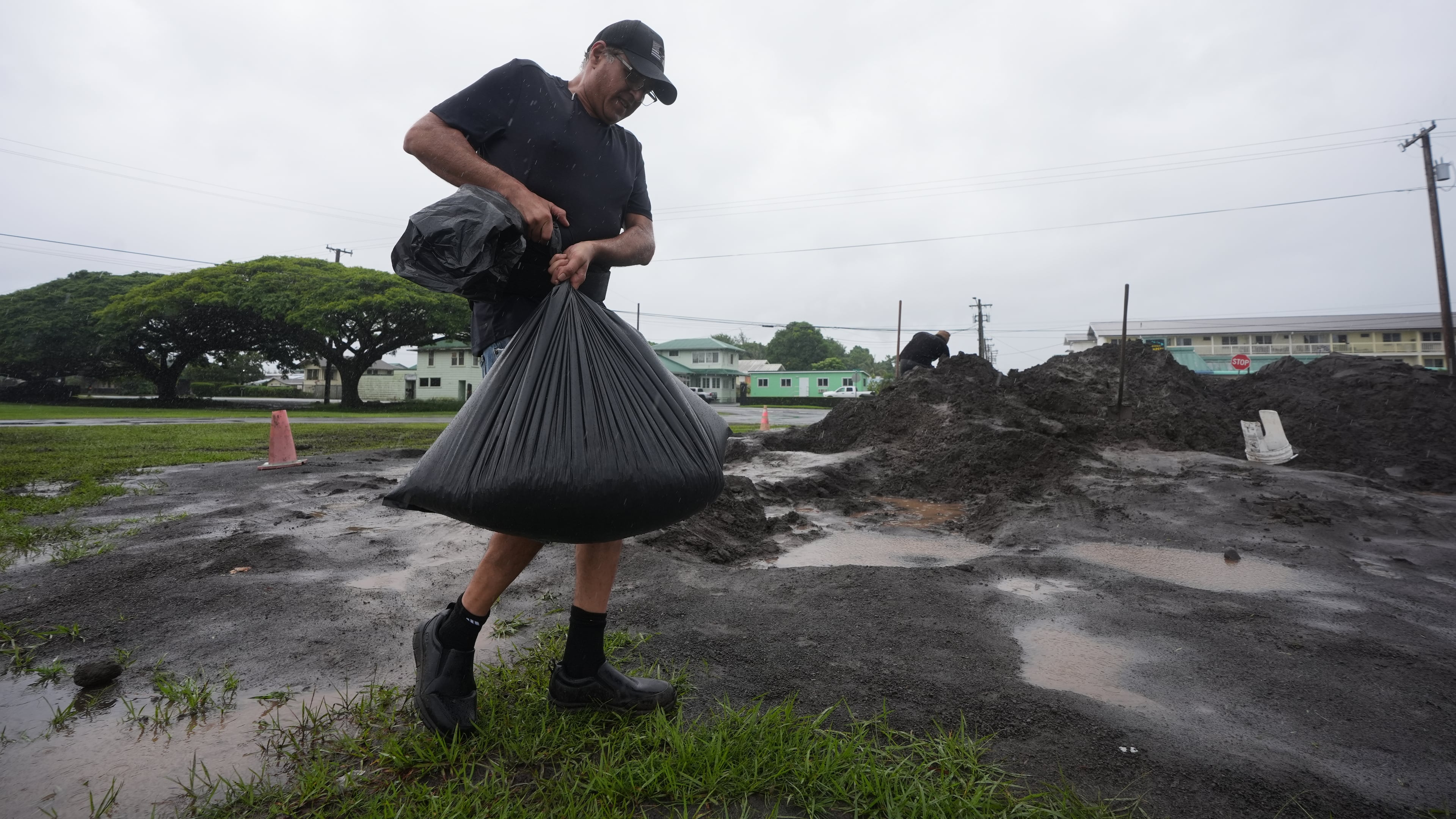 Darren Montalvo carries sand bags he will use to help keep water out of his restaurant as Hurricane Nolo approaches in Hilo, Hawaii, Friday, Sept. 25, 2026. (AP Photo/Gregory Bull)