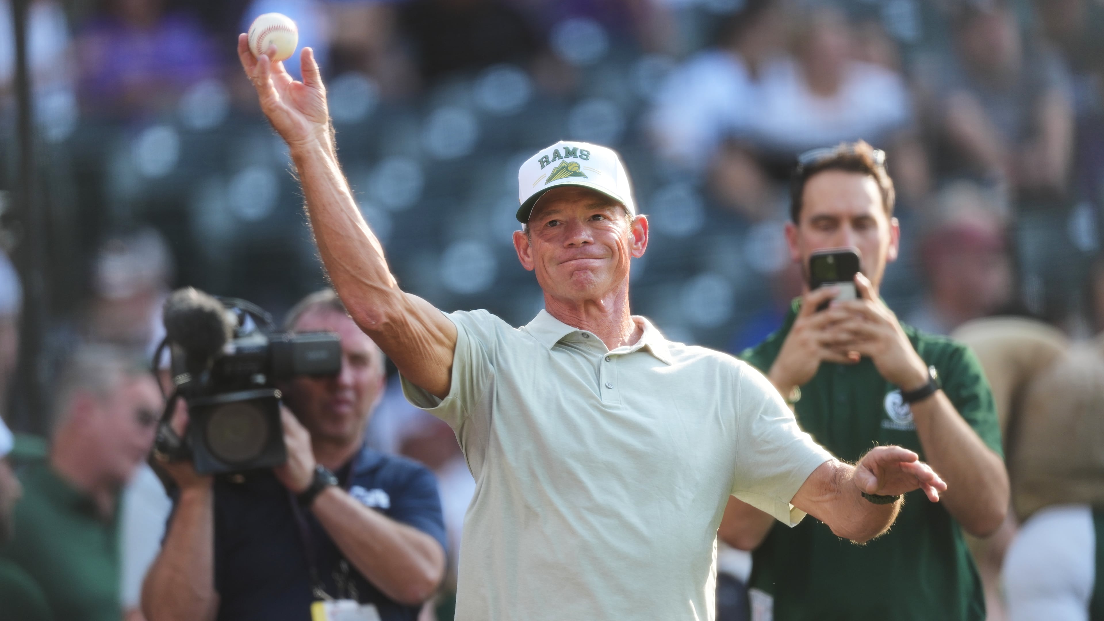 Colorado State University football head coach Jim Mora warms up before throwing the ceremonial first pitch before the Colorado Rockies host the Kansas City Royals in the first inning of a baseball game Saturday, Aug. 1, 2026, in Denver. (AP Photo/David Zalubowski)