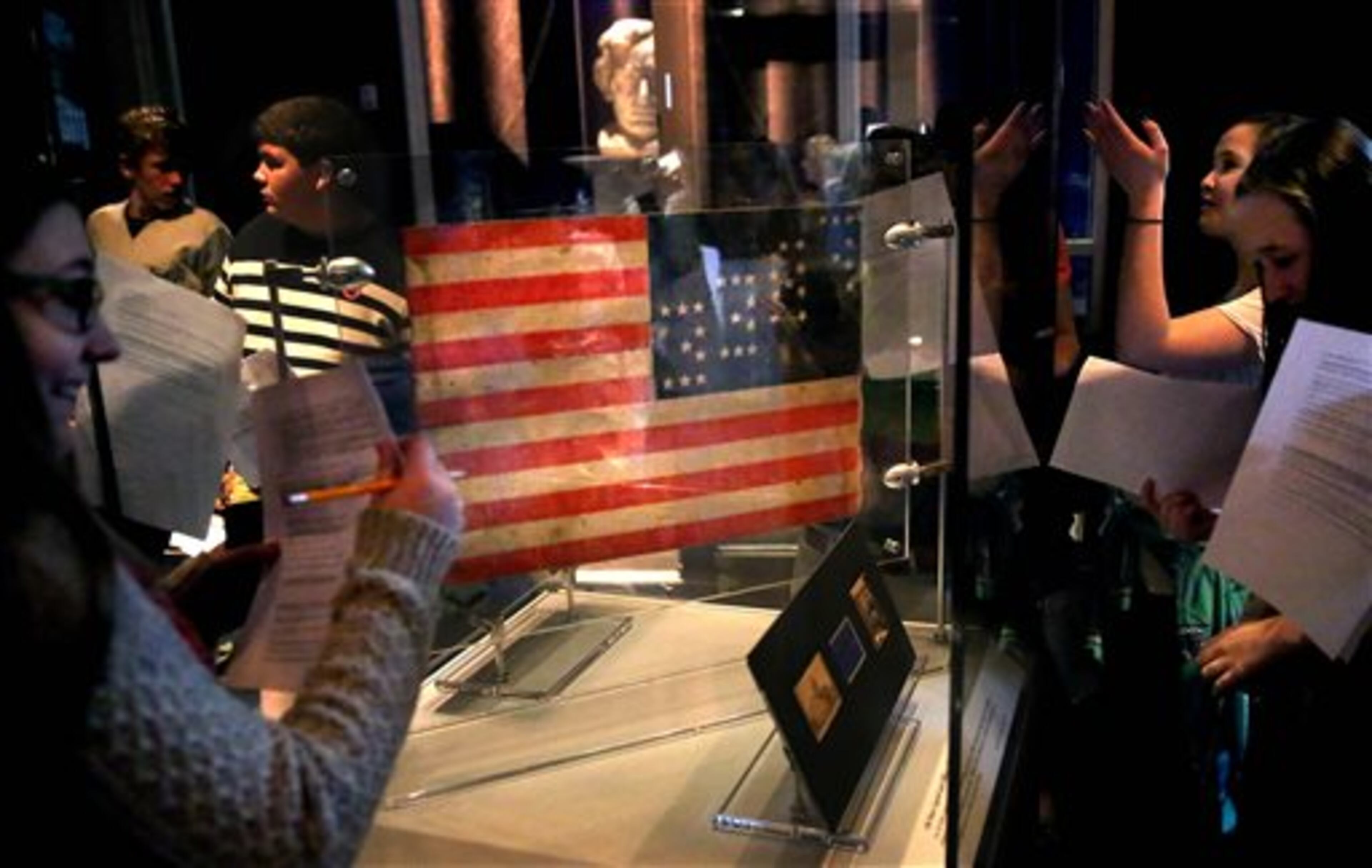 In this Thursday, April 2, 2015 photo, a 35-star American flag that flew from Daniel Bower's sandwich cart during the Springfield funeral of Abraham Lincoln is displayed at the Abraham Lincoln Presidential Museum in Springfield, Ill., as students from Rochester Jr. High School fill out work sheets during a visit. The new exhibit �A Fiendish Assassination�, opened in the Treasures Gallery at the Museum Thursday, and runs until early July. The more than 40 artifacts displayed-many never before seen in public show items related to Lincoln�s death and funeral 150 years ago this year. (AP Photo/The State Journal-Register, David Spencer)