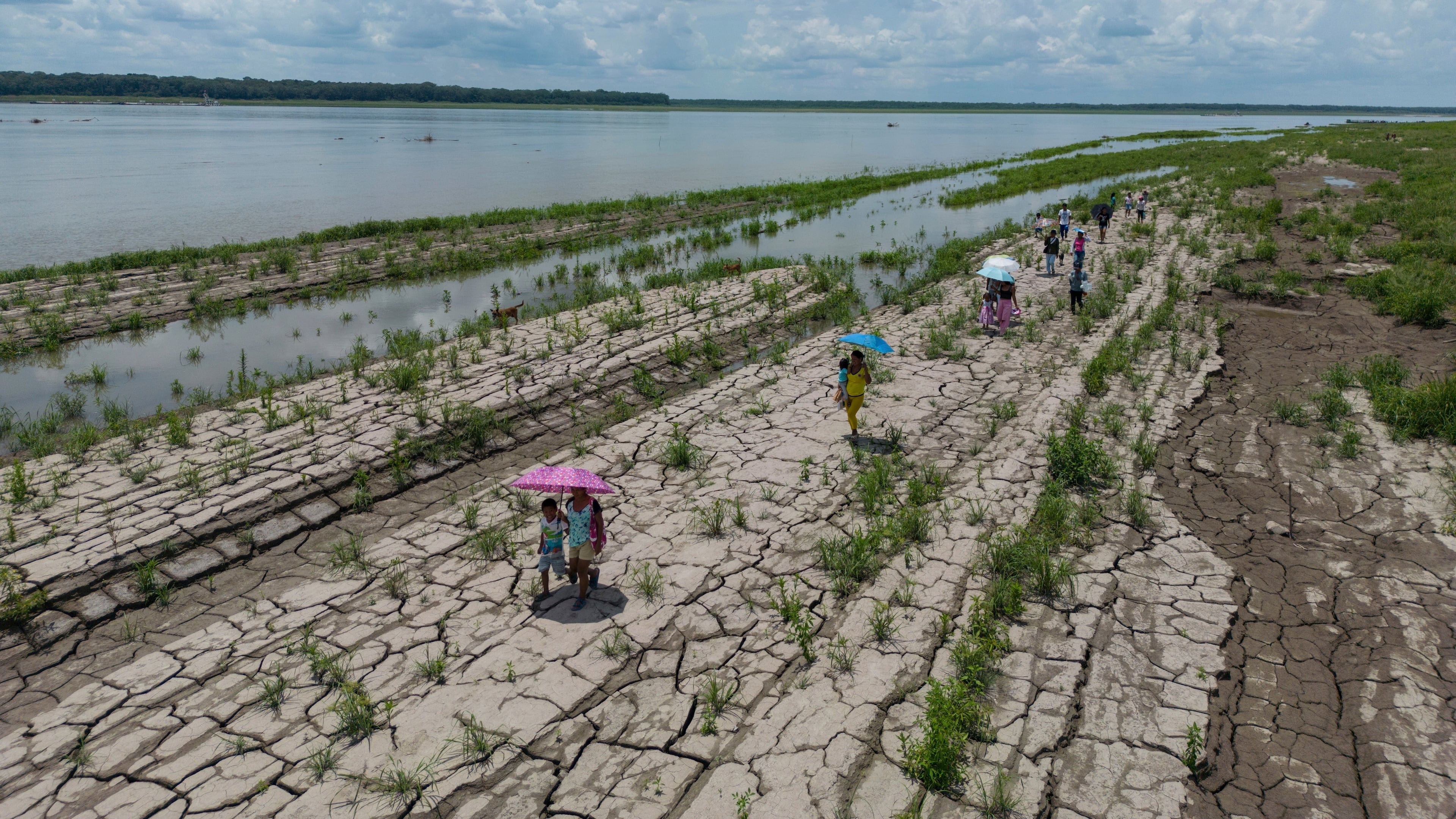 FILE - People walk through a part of the Amazon River that shows signs of drought in Santa Sofia, on the outskirts of Leticia, Colombia, Oct. 20, 2024. (AP Photo/Ivan Valencia, File)