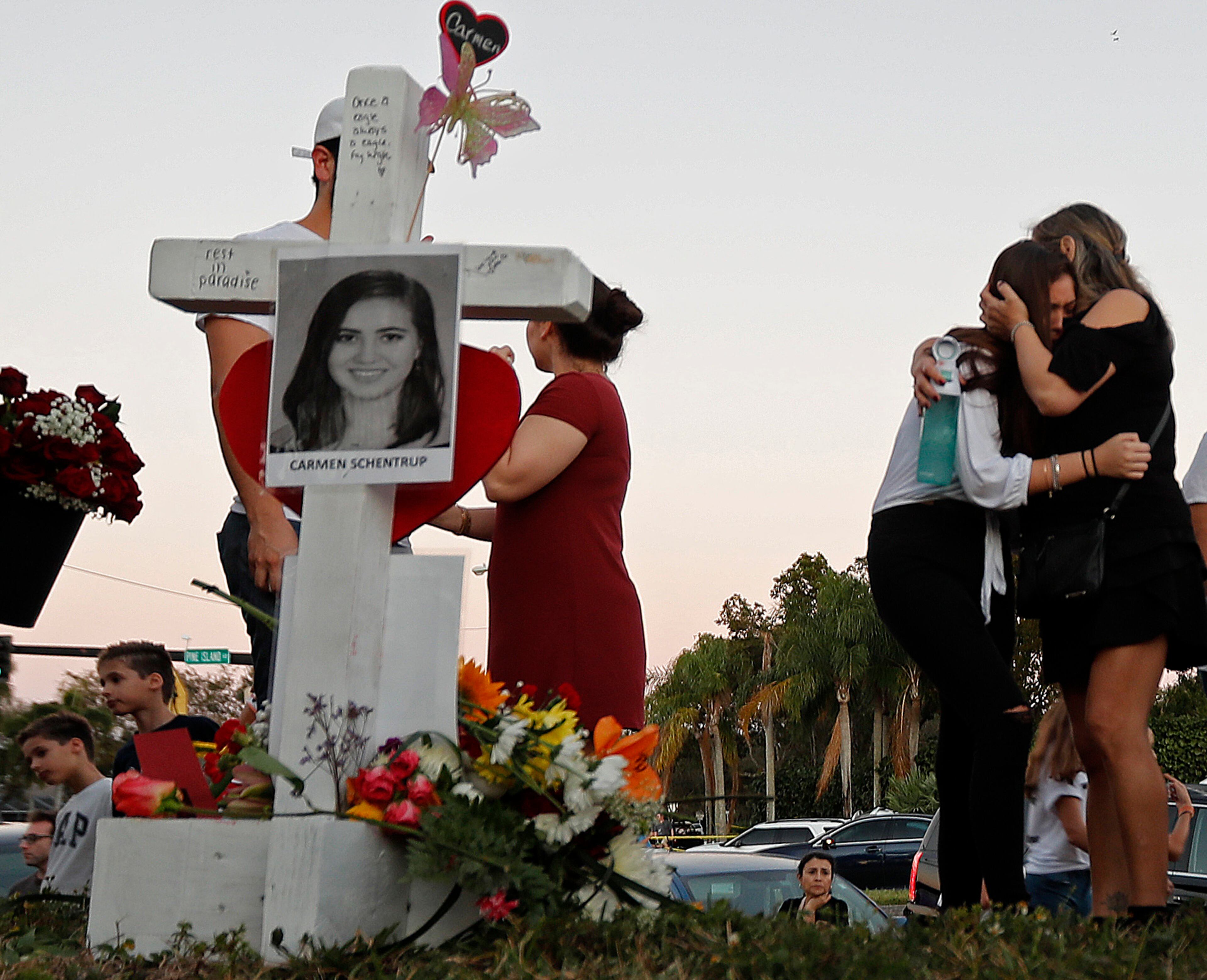 Magaly Newcomb, right comforts her daughter Haley Newcomb, 14, a student at Marjory Stoneman Douglas High School, at a makeshift memorial for Carmen Schentrup outside the school, in Parkland, Fla., Sunday, Feb. 18, 2018. Nikolas Cruz, a 19-year-old who had been expelled from the school, is being held without bail in the Broward County Jail, accused of 17 counts of first-degree murder. (AP Photo/Gerald Herbert)
