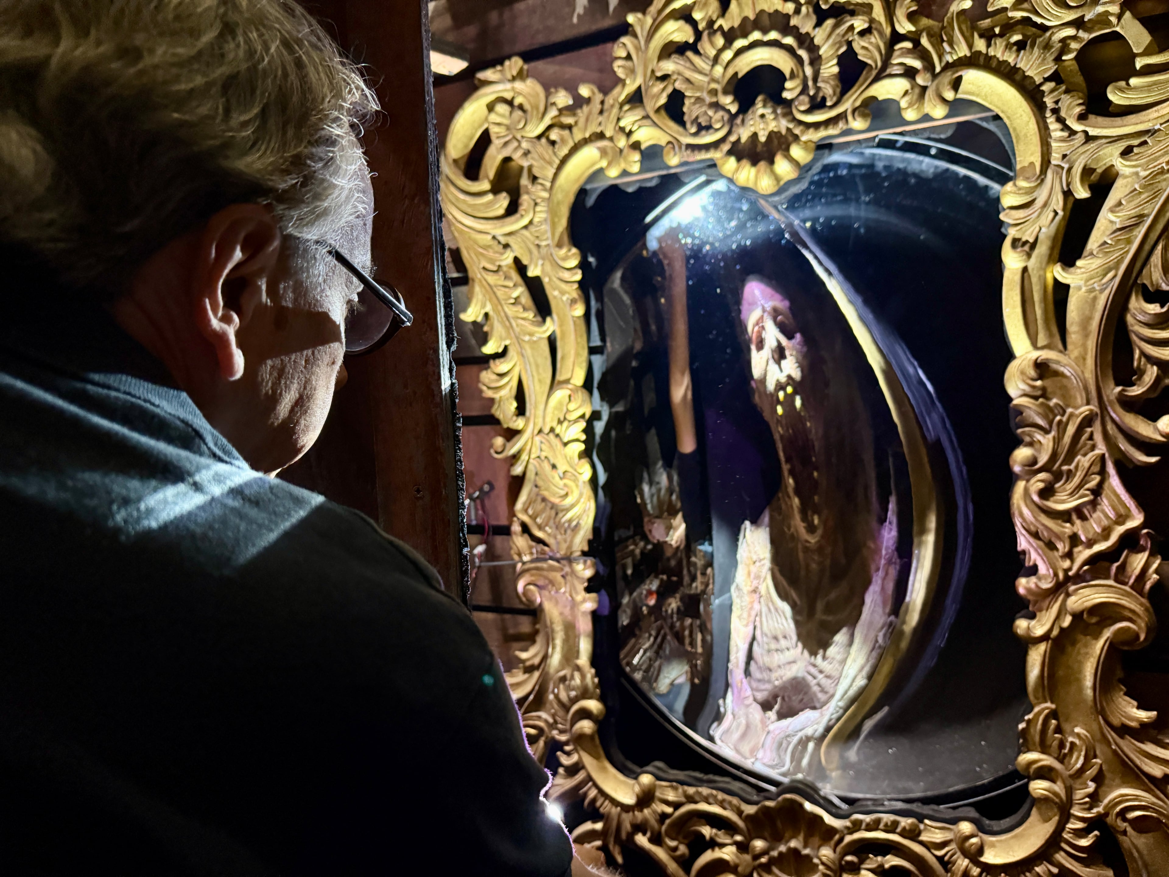 Netherworld co-creator Ben Armstrong peers into a mirror that creates an optical illusion inside this year's "Monsters Attack" maze.