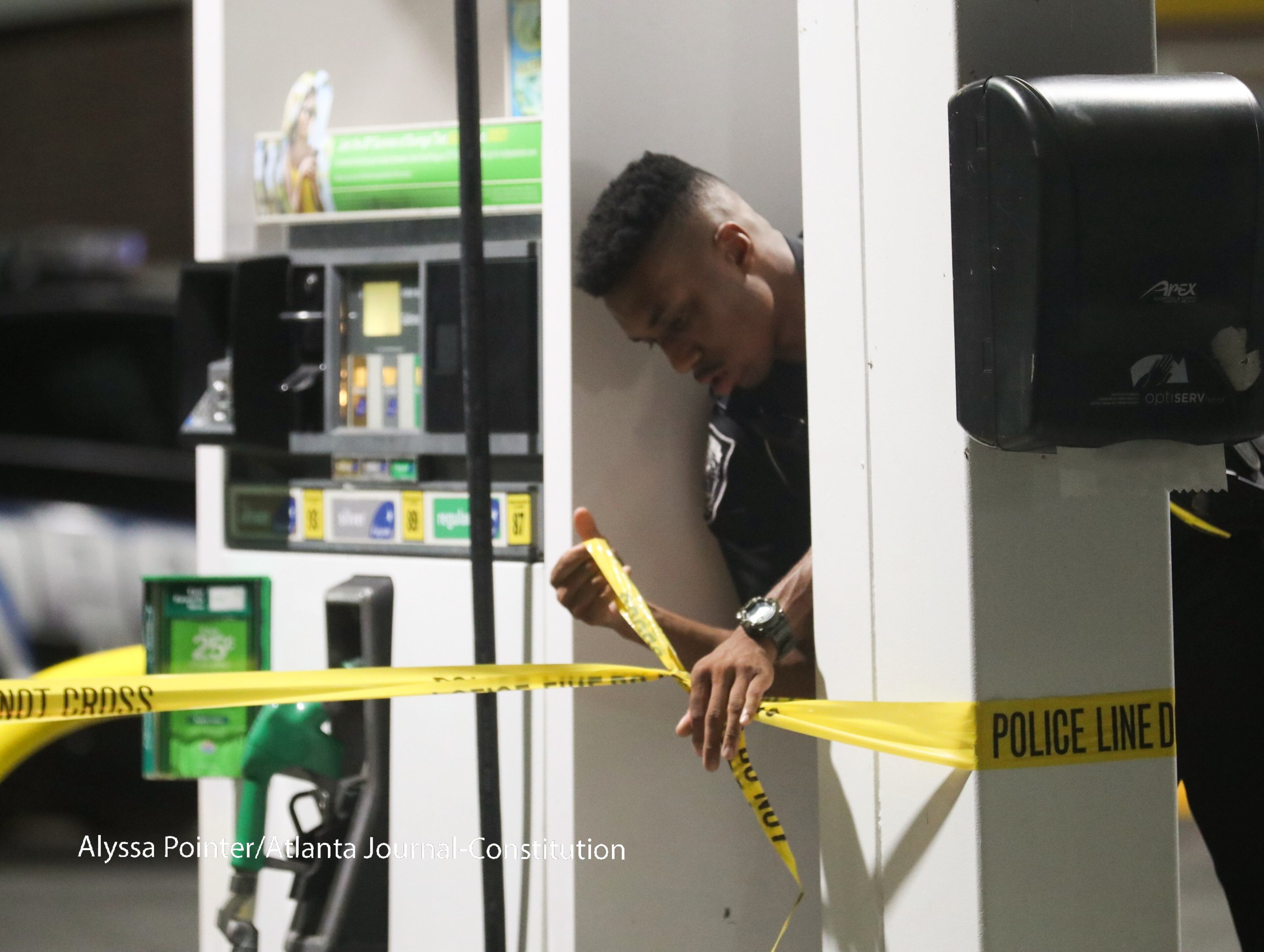 DeKalb and Gwinnett police officers place crime scene tape at a BP gas station Tuesday. ALYSSA POINTER / ALYSSA.POINTER@AJC.COM