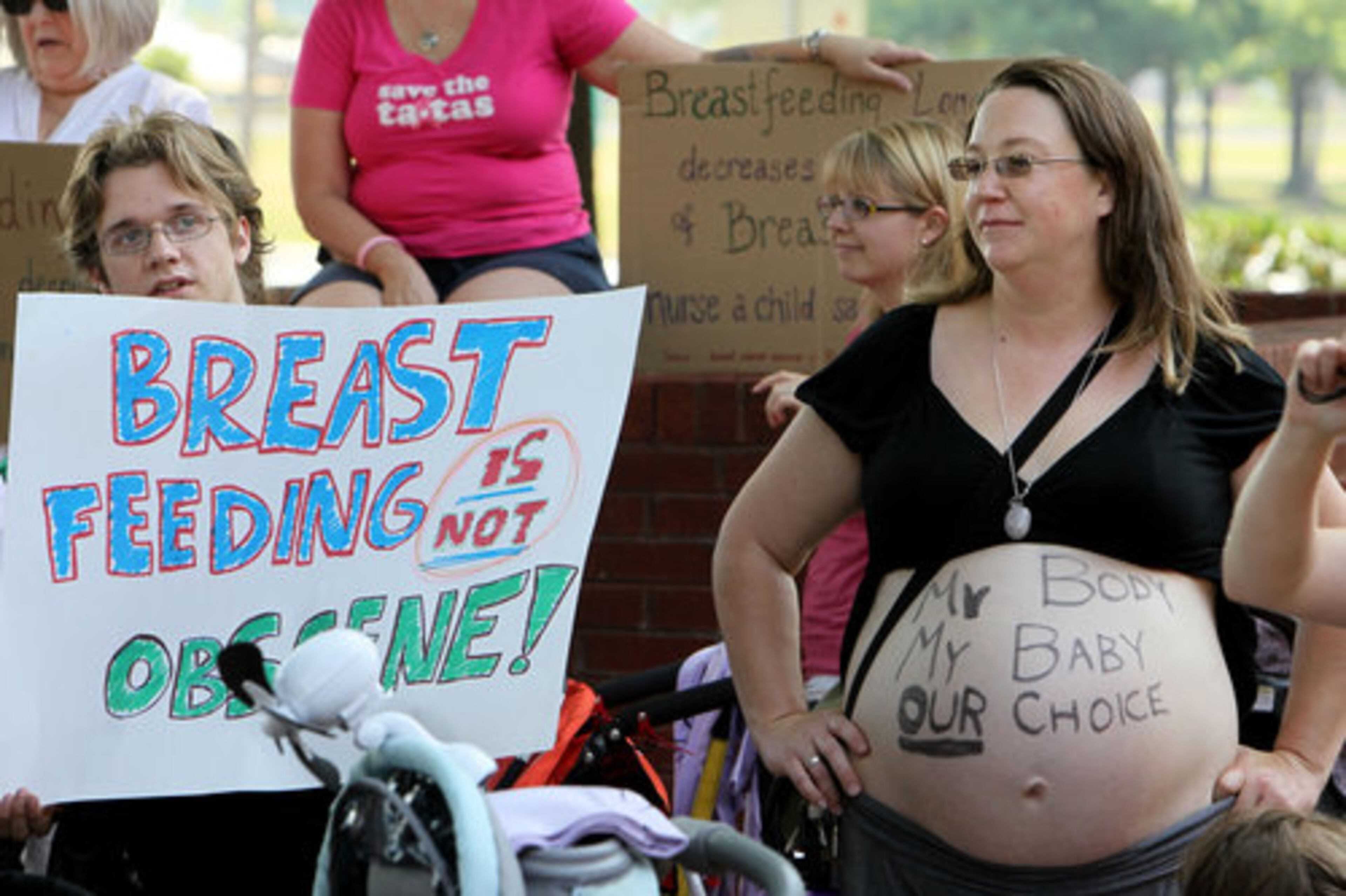 BREASTFEEDING BROUHAHA--Jake Warner(left, from Snellville) waves a sign while Dawn Rush (Stone Mountain), who is due to deliver her baby in three weeks, wears hers on her belly as about three hundred woman, children and husbands stage a "Nurse In" on Monday May 23rd in front of the Forest Park City Hall to protest a new law limiting public breast feeding. The ordinance prohibits breast feeding children older than two in public.
