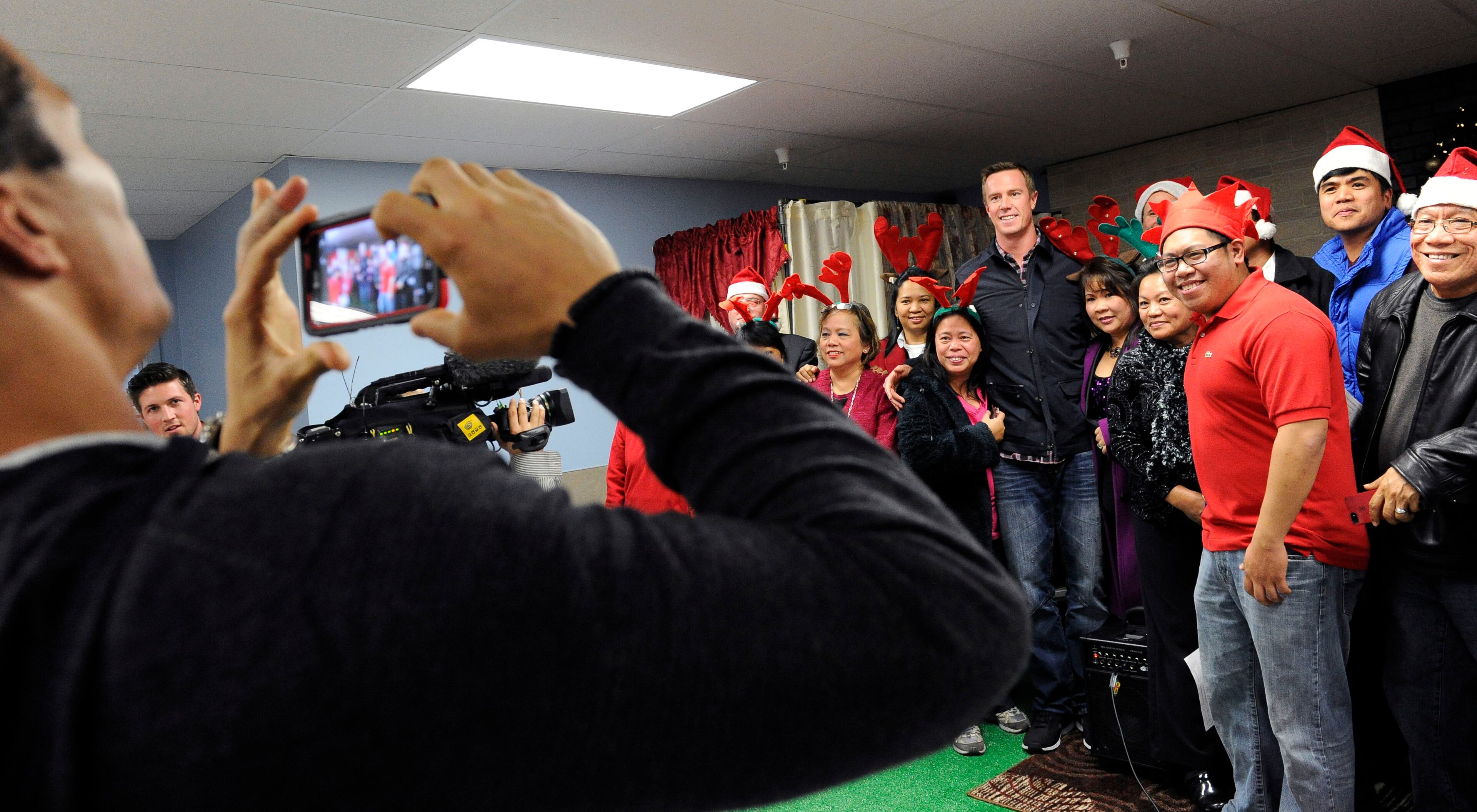 Atlanta Falcons tight end Tony Gonzalez, left, takes a picture of quarterback Matt Ryan posing with members of a choir that sung for children during the "Shop with a Jock" program, which provides a $100 gift card and a shopping experience to children from an Atlanta-area mission at a Walmart department store, Tuesday, Dec. 11, 2012, in Suwanee.
