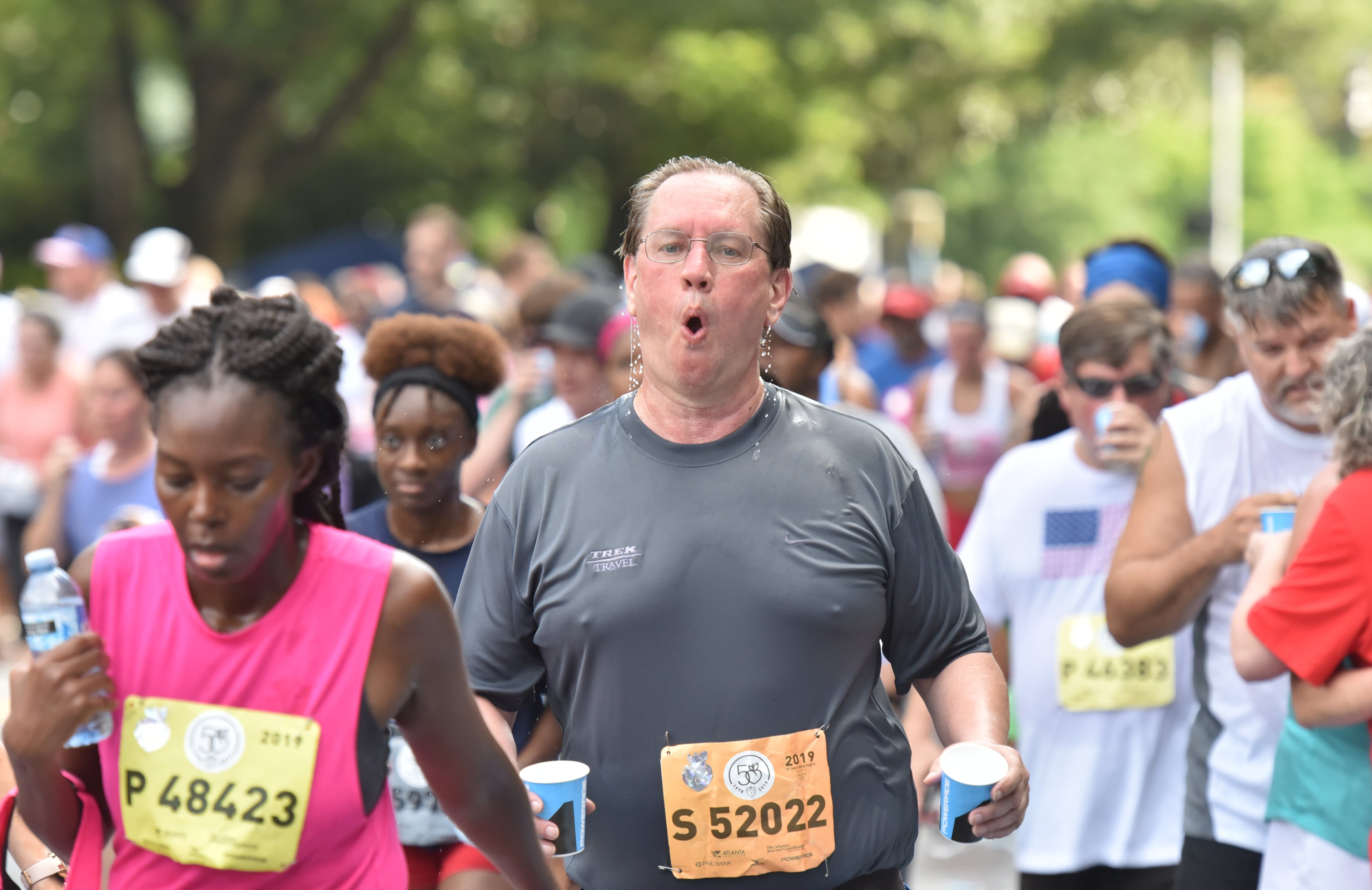 A runner cools off with a cup of water at a water station at Shepherd Center during the 50th AJC Peachtree Road Race on Thursday, July 4, 2019. (Hyosub Shin / Hyosub.Shin@ajc.com)