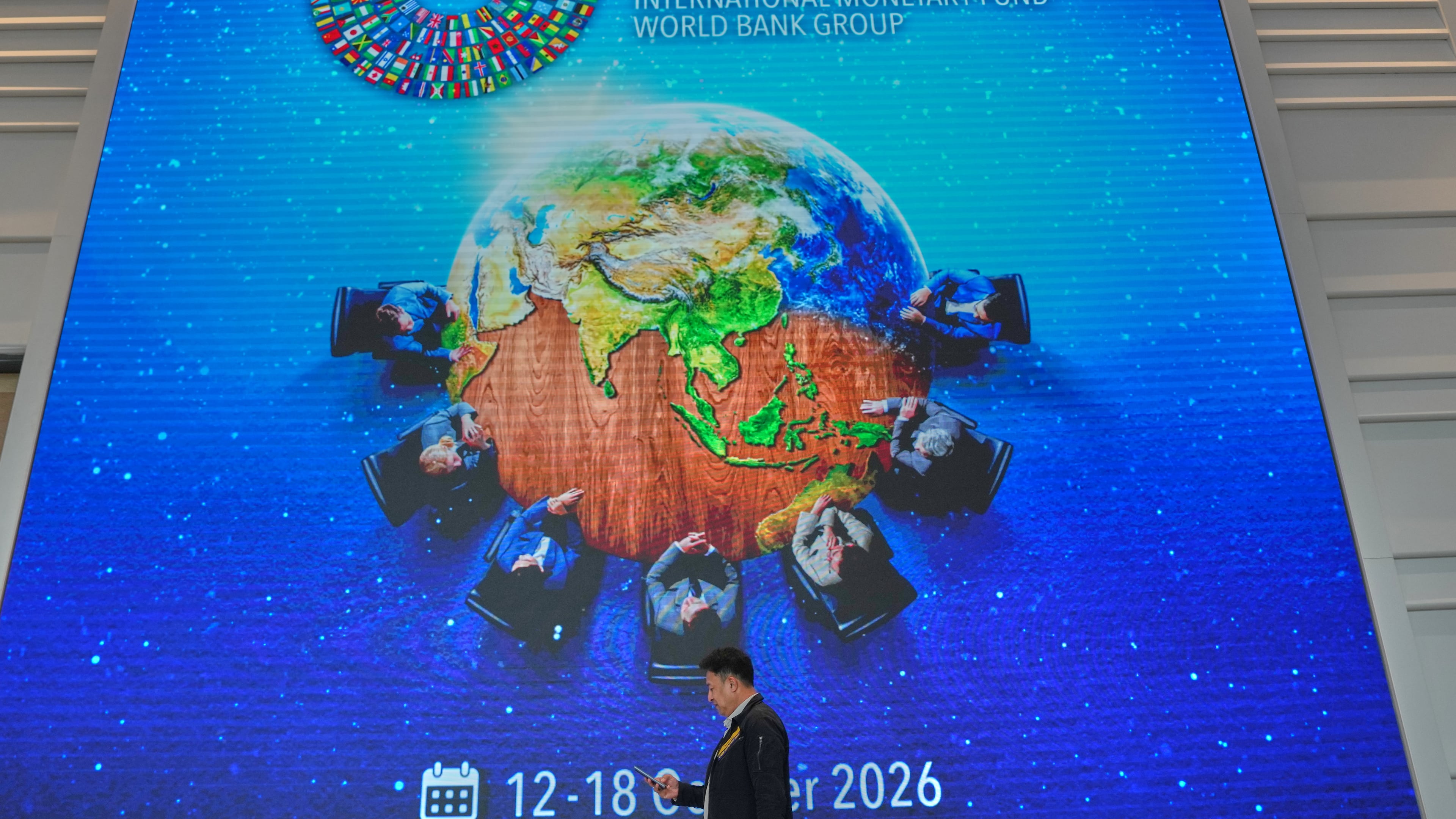 A man walks in front of giant billboard at the Queen Sirikit National Convention Center ahead of the annual meetings of the International Monetary Fund (IMF) and the World Bank Group in Bangkok, Thailand, Friday, Oct. 9, 2026. (AP Photo/Sakchai Lalit)