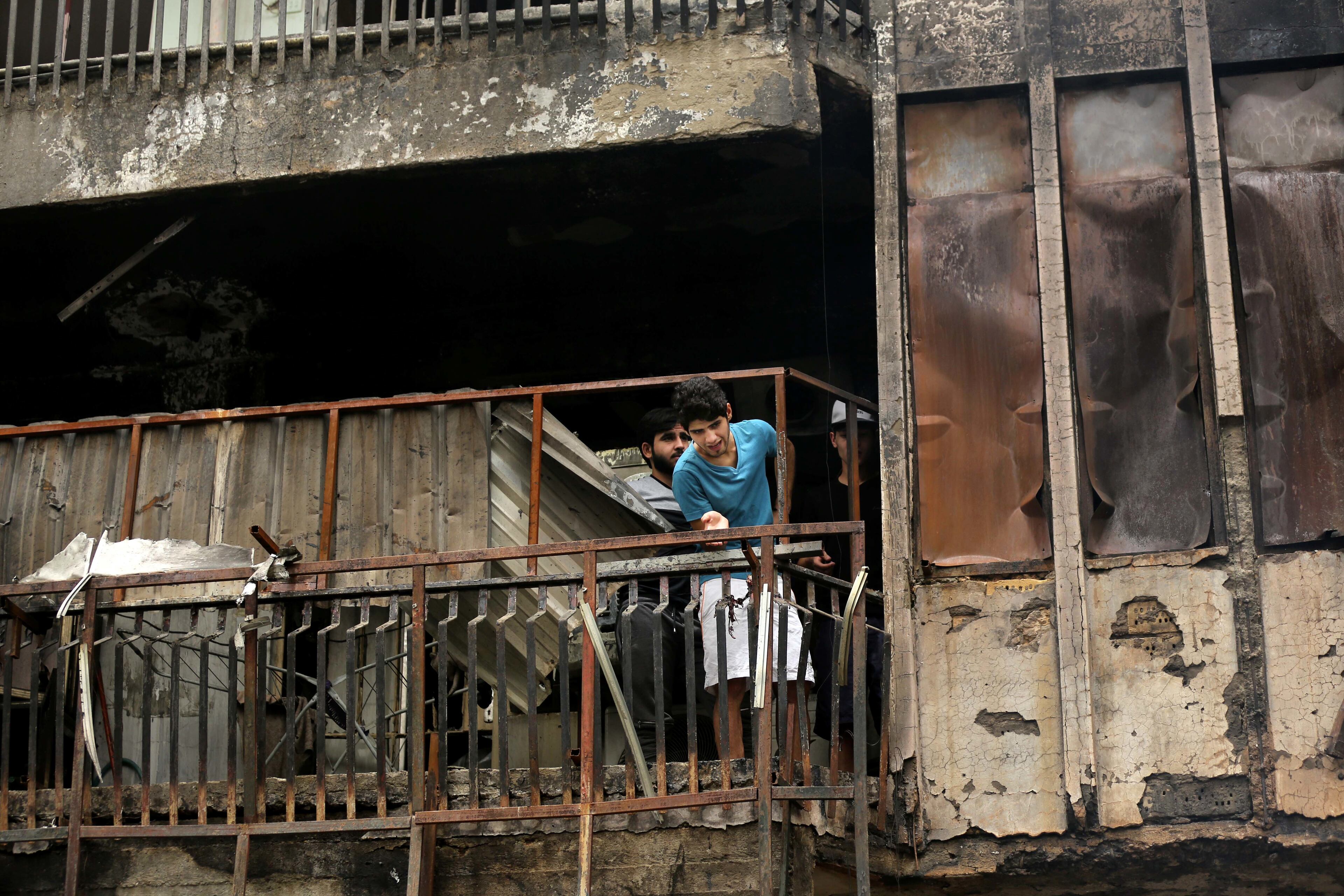 Iraqi men looks for victims who went missing after a car bomb hit Karada, a busy shopping district in the center of Baghdad, Iraq, Sunday, July 3, 2016. Dozens of people have been killed and more than 100 wounded in two separate bomb attacks in the Iraqi capital Sunday morning, Iraqi officials said. (AP Photo/Hadi Mizban)