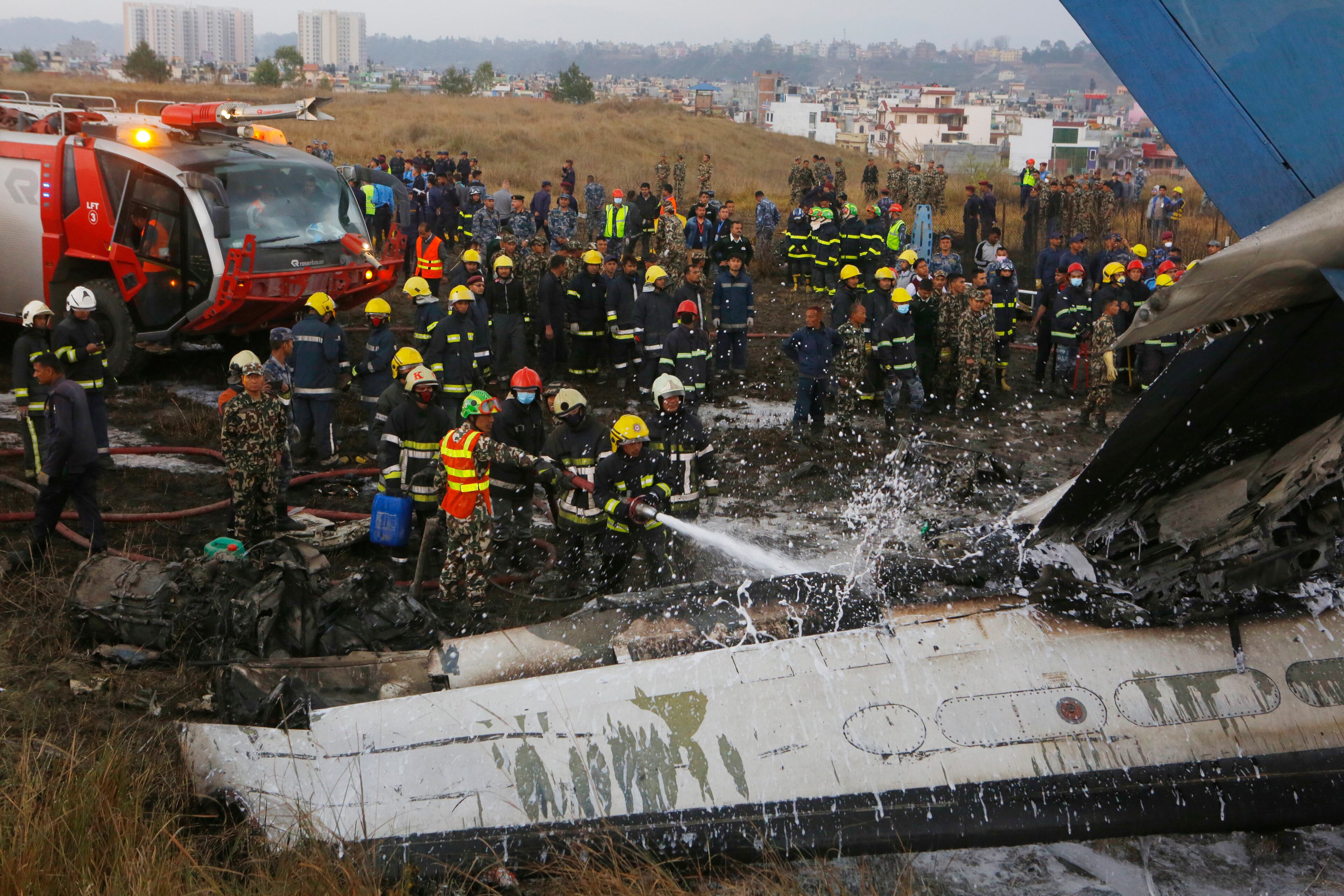 Nepalese firemen spray water on the debris after a passenger plane from Bangladesh crashed at the airport in Kathmandu, Nepal, Monday, March 12, 2018. The passenger plane carrying 71 people from Bangladesh crashed and burst into flames as it landed Monday in Kathmandu, Nepal's capital, killing dozens of people, officials said. (AP Photo/Niranjan Shreshta)