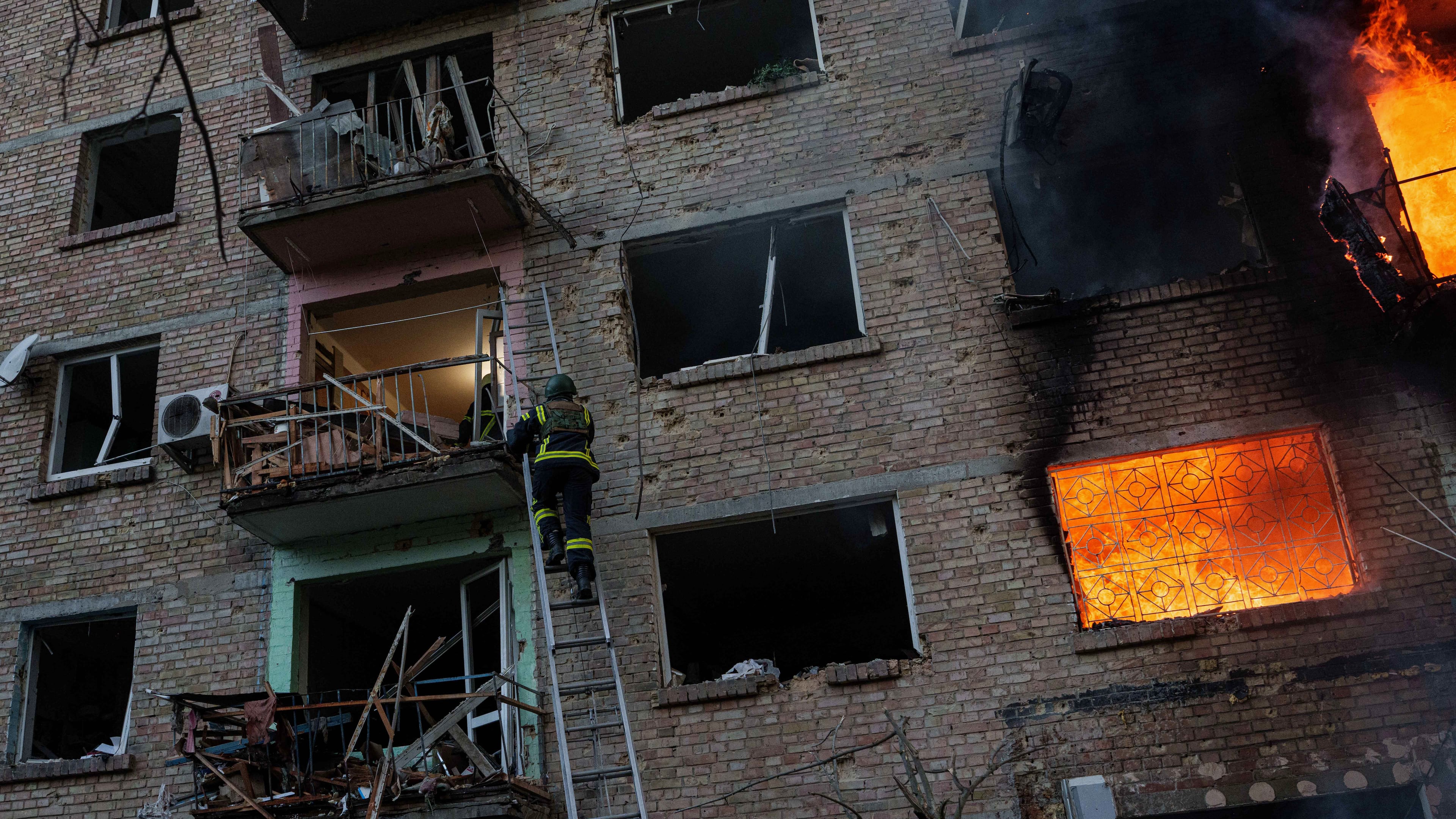A rescue worker climbs on a ladder to help evacuate people from a residential building being destroyed after a Russian strike on Kyiv, Ukraine, Sunday, May 24, 2026. (AP Photo/Evgeniy Maloletka)
