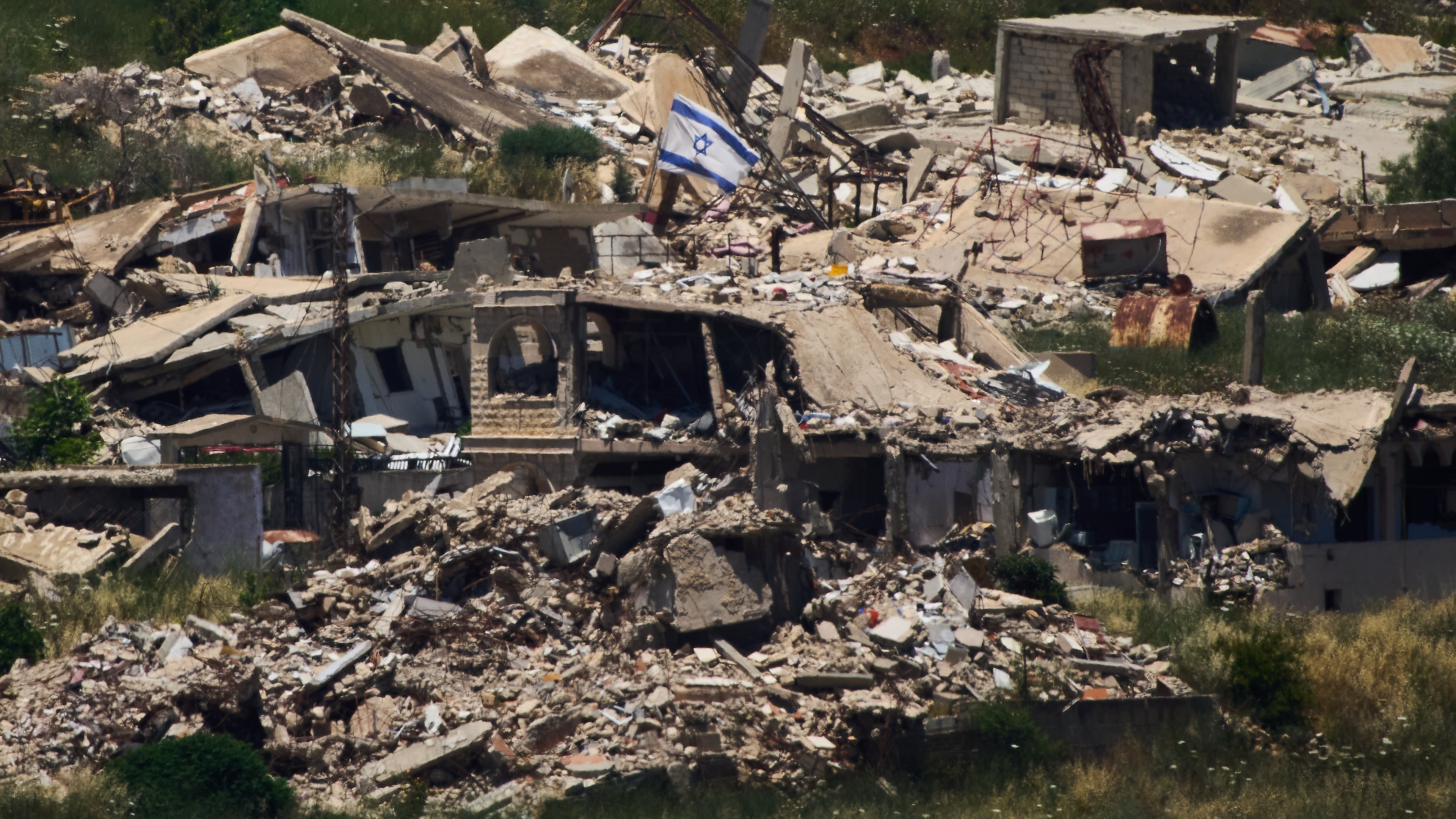An Israeli flag hangs on a destroyed building in southern Lebanon as seen from northern Israel, Thursday June 4, 2026. (AP Photo/Ariel Schalit)