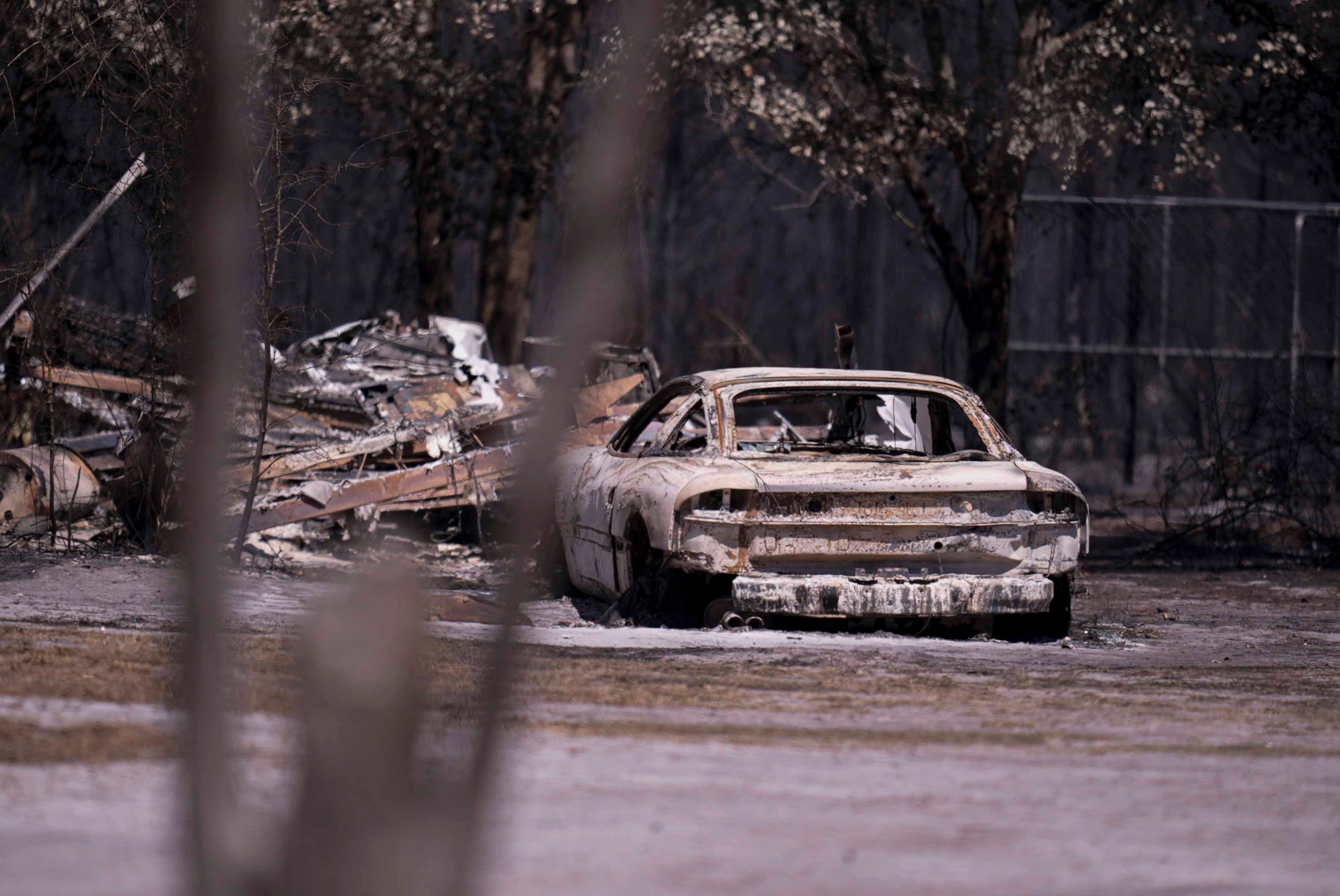 A burned vehicle sits near a home as the Brantley Highway 82 fire burns on Thursday, April 23, 2026, near Nahunta. (Mike Stewart/AP)