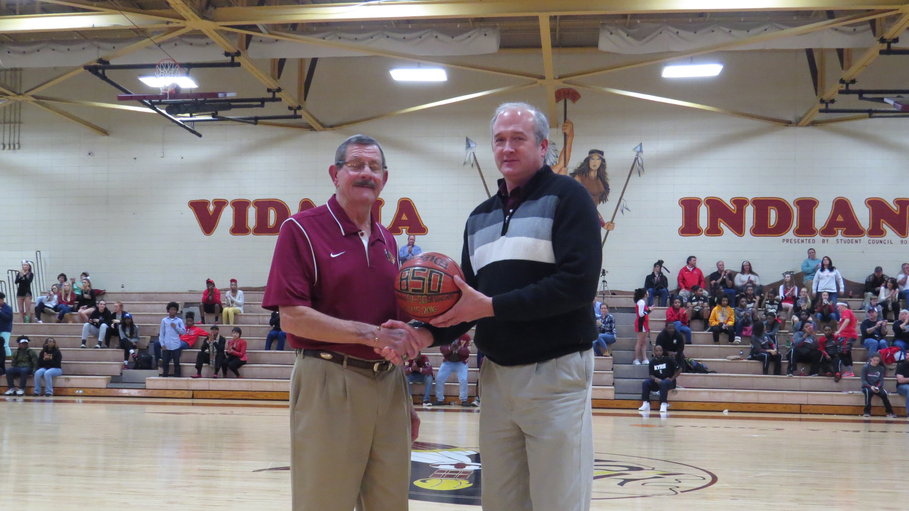 Vidalia Lady Indians coach Chunk Reid, left, and Vidalia principal John Sharpe shake hands at mid-court on Tuesday, Jan. 19, 2016 during halftime of the Lady Indians' basketball game against Bacon County. Reid was being honored for his 850th career win as Vidalia's girls basketball coach. (Special to AJC.com)