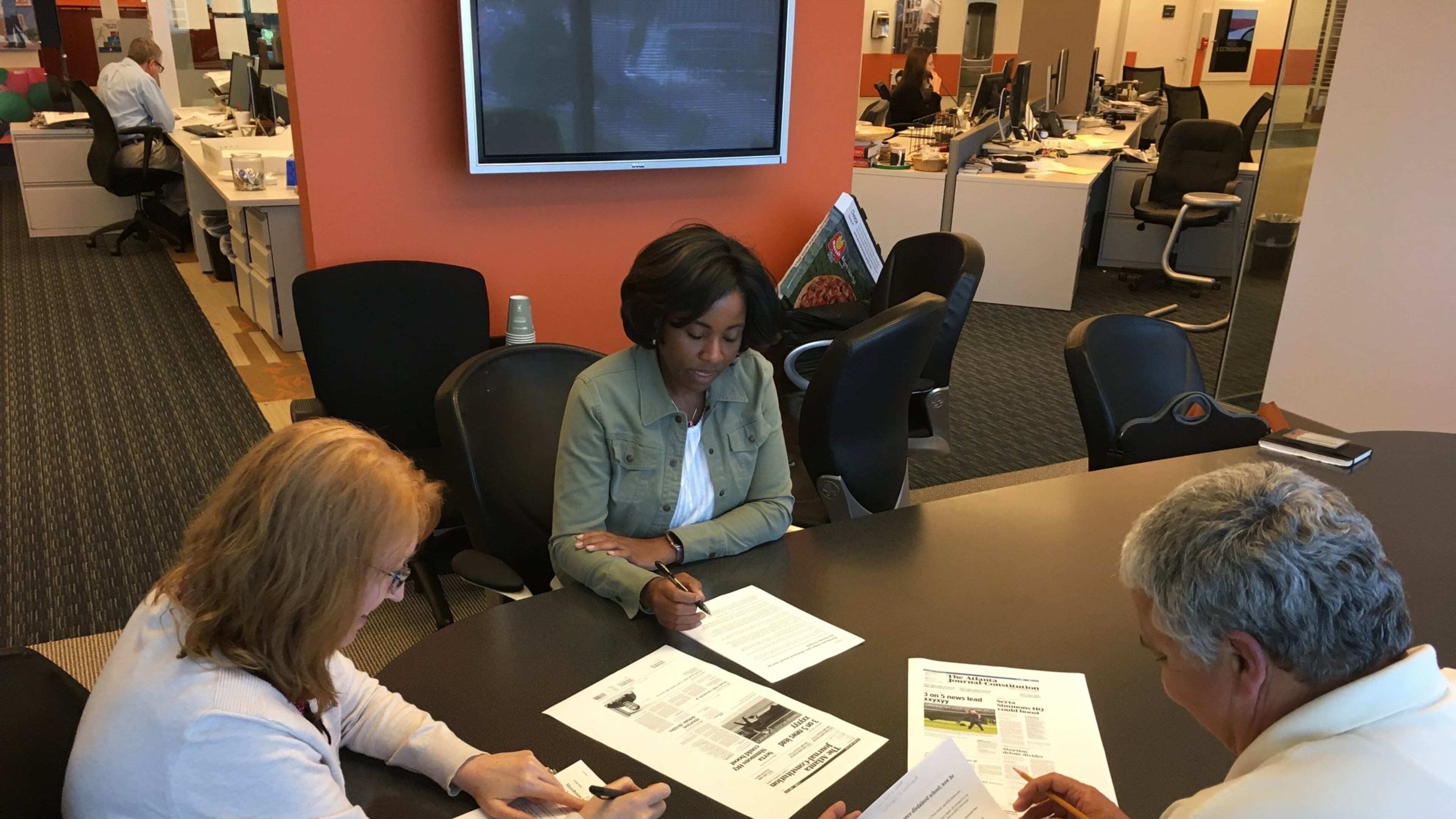 Laura Weaver (from left), Tracy Brown and Charlie Noell work on headlines for Saturday’s A1. Holly Steel / hsteel@ajc.com