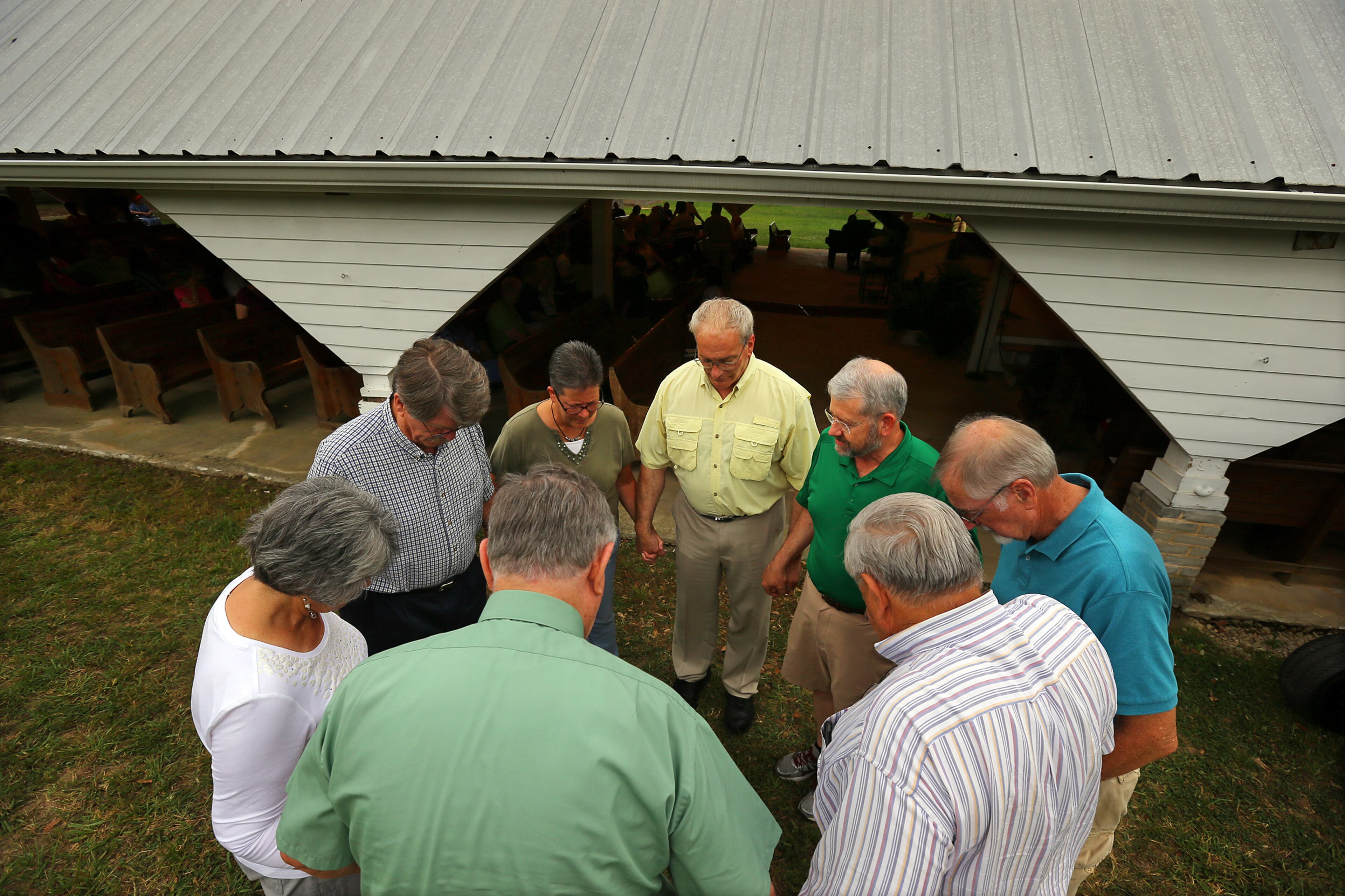 Camp attendees circle for a prayer beside the tabernacle built in 1891 before the beginning of the evening worship service at the Smyrna Presbyterian Church camp meeting on Tuesday, June 24, 2014, in Conyers.