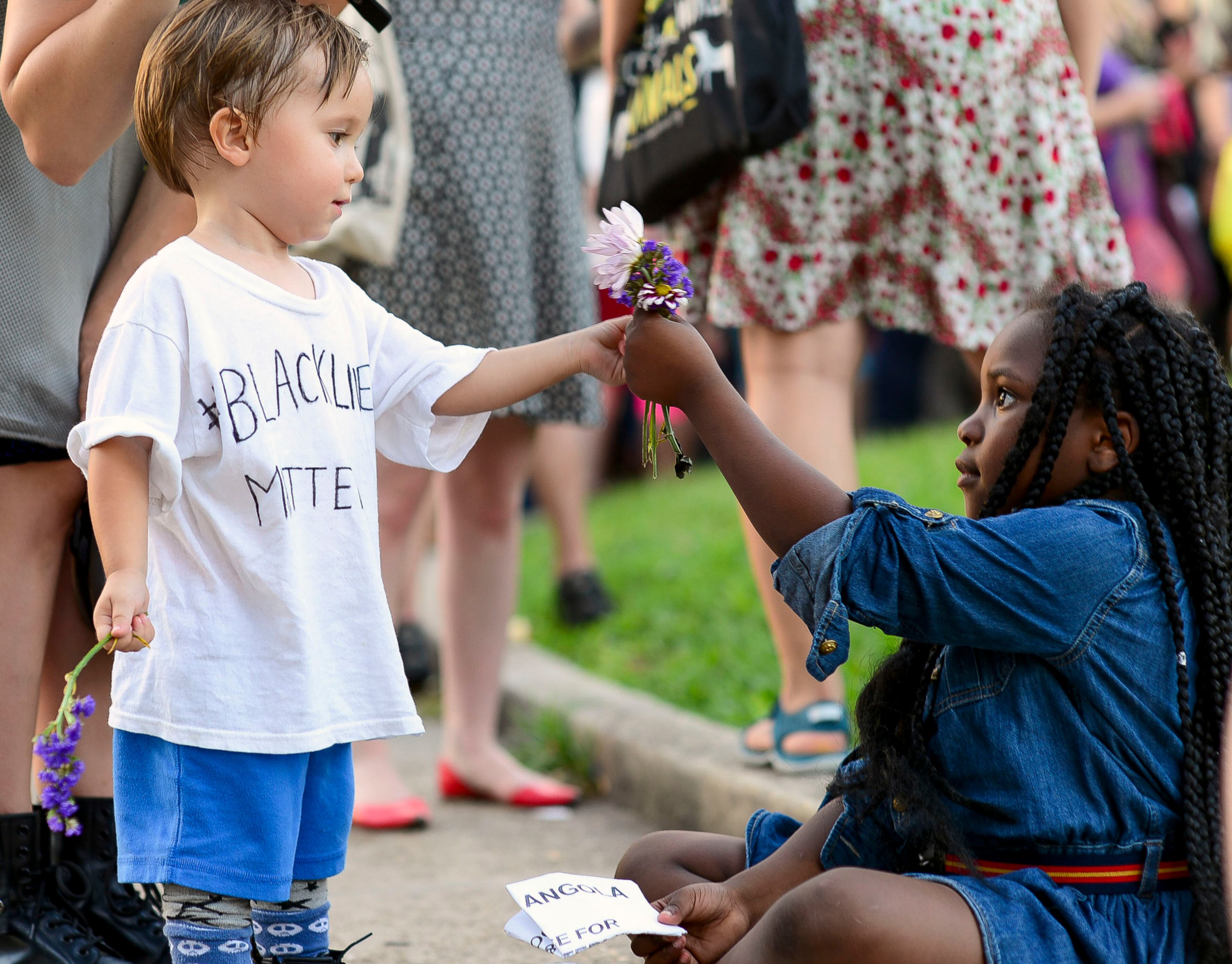 Lucien Novak, 2, left, shares his flowers with La'Nae Hartford, 5, at Lee Circle in Center City during a protest, Friday, July 8, 2016 in New Orleans. (Maggie Andresen/NOLA.com The Times-Picayune via AP)