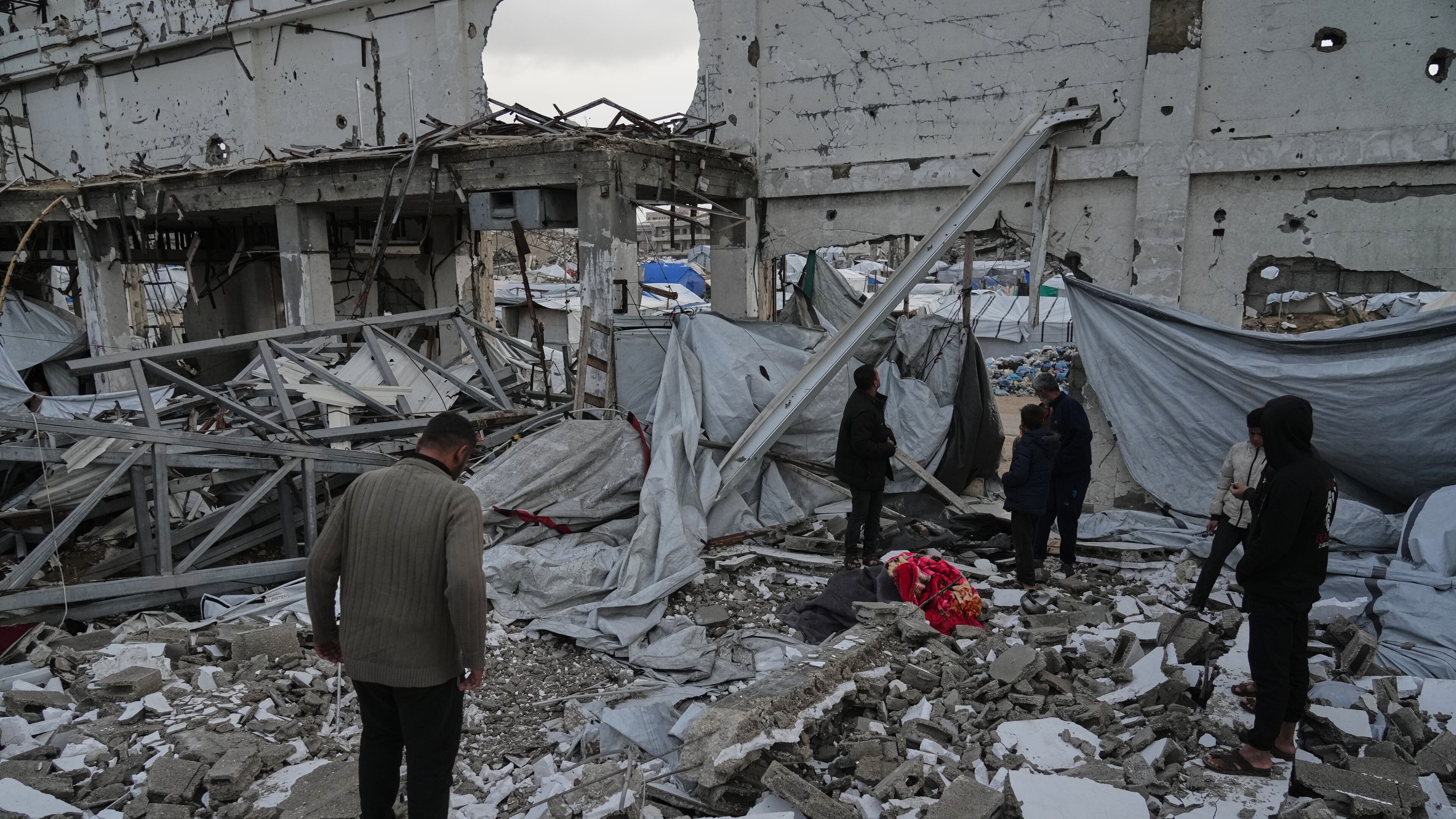 People inspect the site where at least four Palestinians died following the collapse of walls onto tents sheltering displaced people in Gaza City amid rainfall and strong winds, Tuesday, Jan. 13, 2026. (AP Photo/Jehad Alshrafi)
