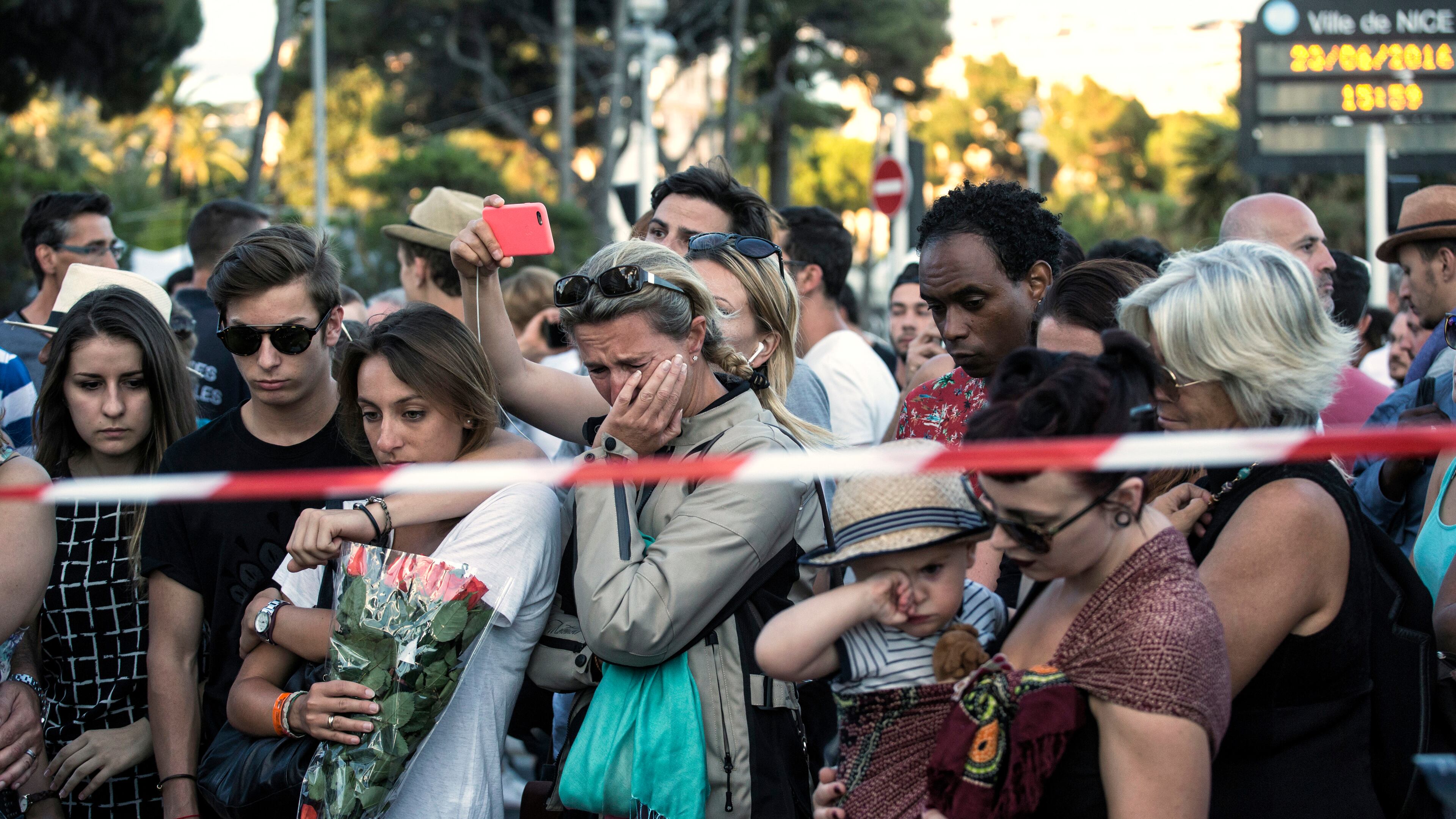 People react as they gather at a makeshift memorial to honor the victims of the Bastille Day attack in Nice, France. A truck mowed through revelers gathered for fireworks, killing 84. (AP Photo/Laurent Cipriani)