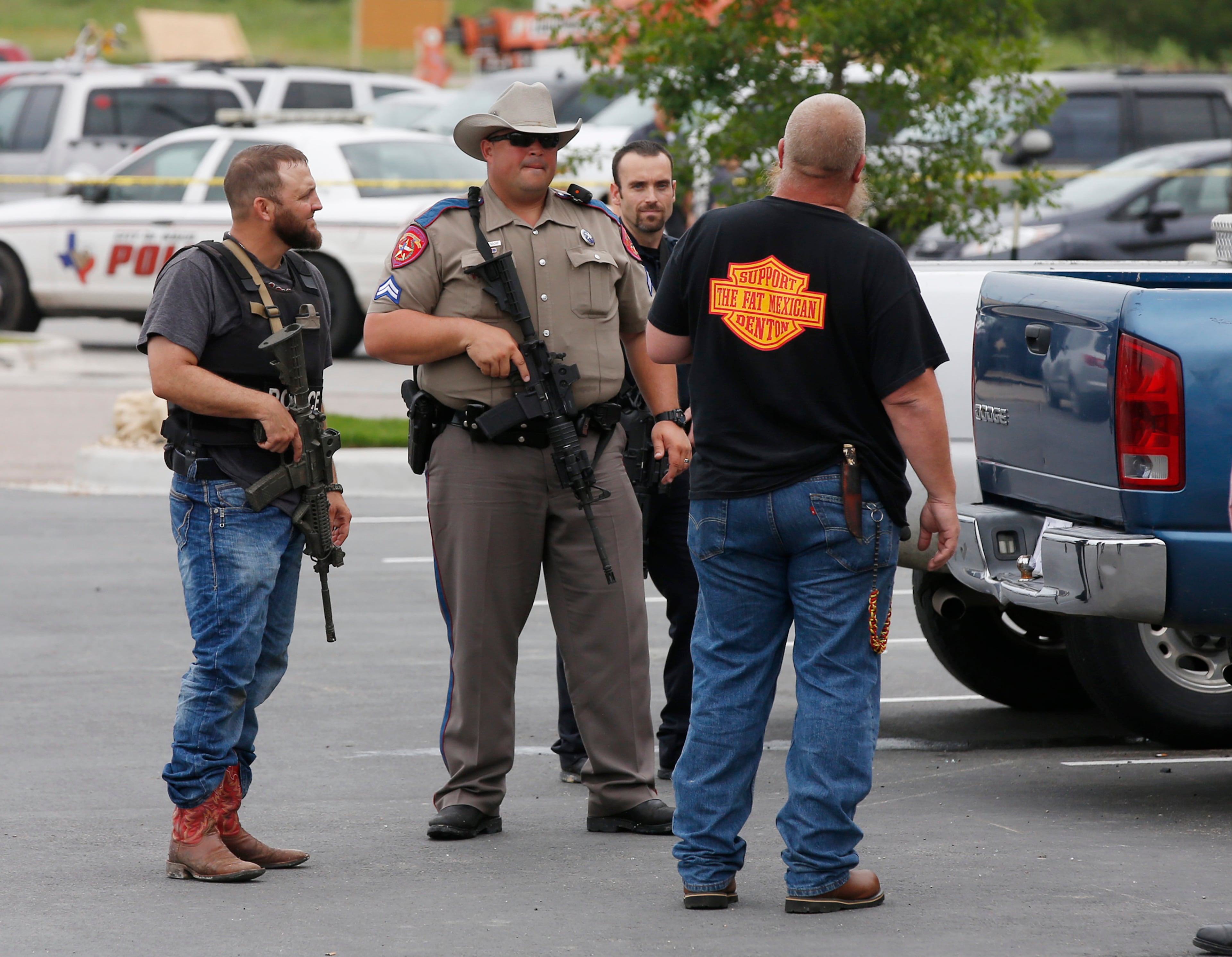 Law enforcement officers talk to a man near the parking lot of a Twin Peaks Restaurant Sunday, May 17, 2015, in Waco, Texas, after a shooting involving rival biker gangs. Waco police Sgt. W. Patrick Swanton told KWTX-TV there were �multiple victims� after gunfire erupted between the gang members. (Rod Aydelotte/Waco Tribune Herald via AP)