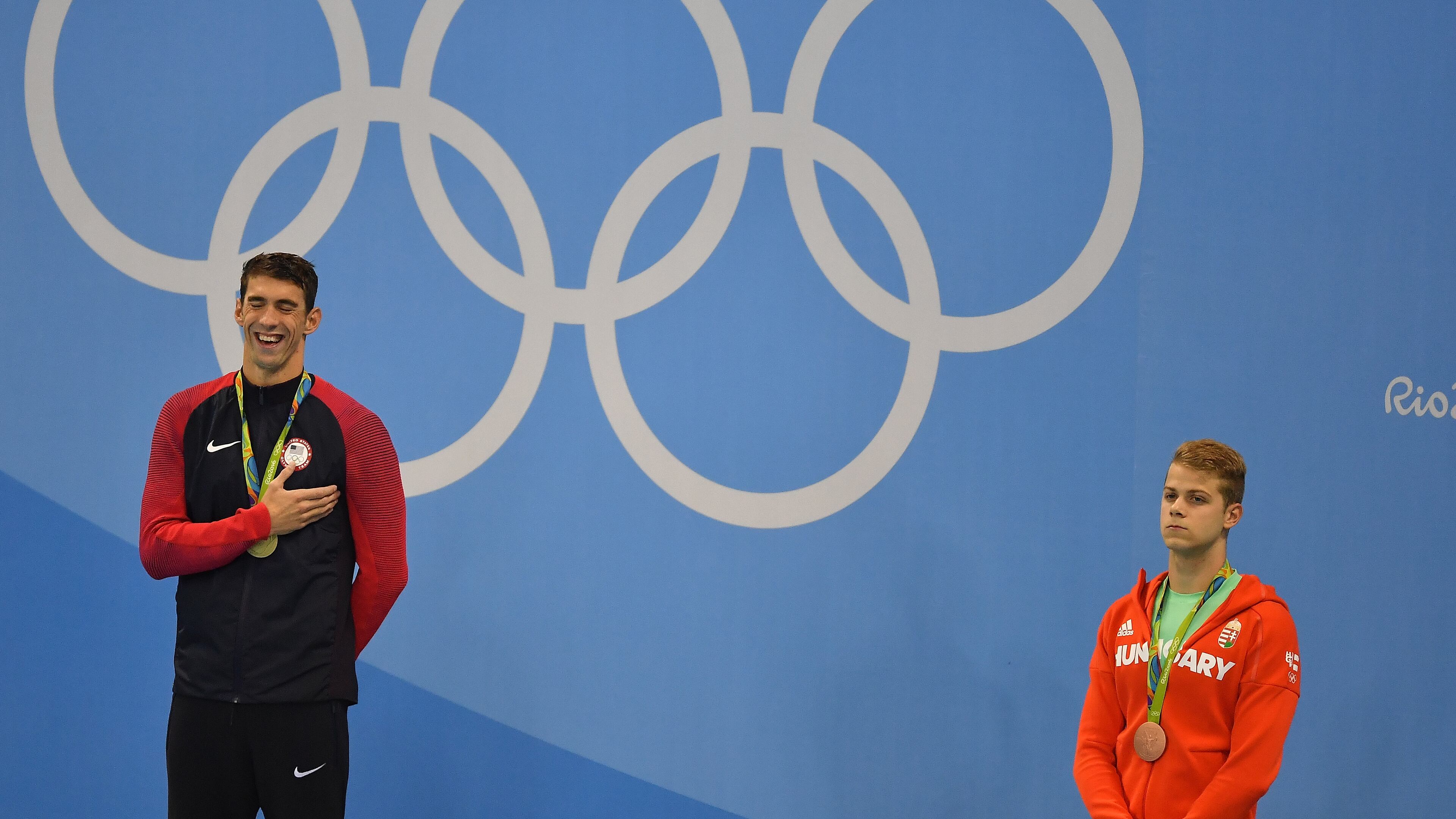 RIO DE JANEIRO, BRAZIL - AUGUST 09: Gold medalist Michael Phelps poses as bronze medalist Tamas Kenderesi of Hungary look on during the medal ceremony for the Men's 200m Butterfly Final on Day 4 of the Rio 2016 Olympic Games at the Olympic Aquatics Stadium on August 9, 2016 in Rio de Janeiro, Brazil. (Photo by Pascal Le Segretain/Getty Images)