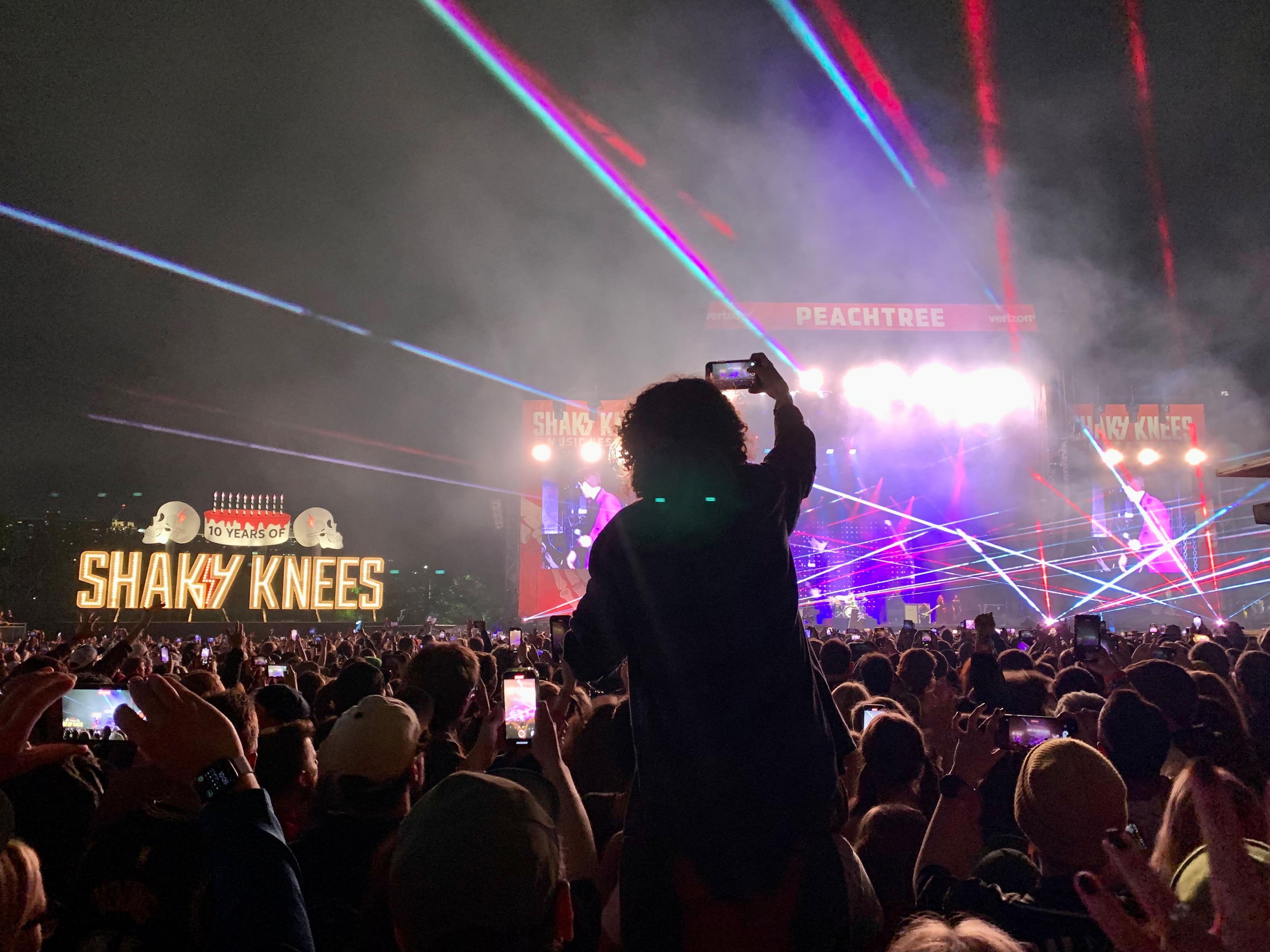 A fan sits on another person's shoulders above the crowd at the Killers performance at Shaky Knees music festival on Friday, May 5, 2023. (Taylor Croft/taylor.croft@ajc.com)