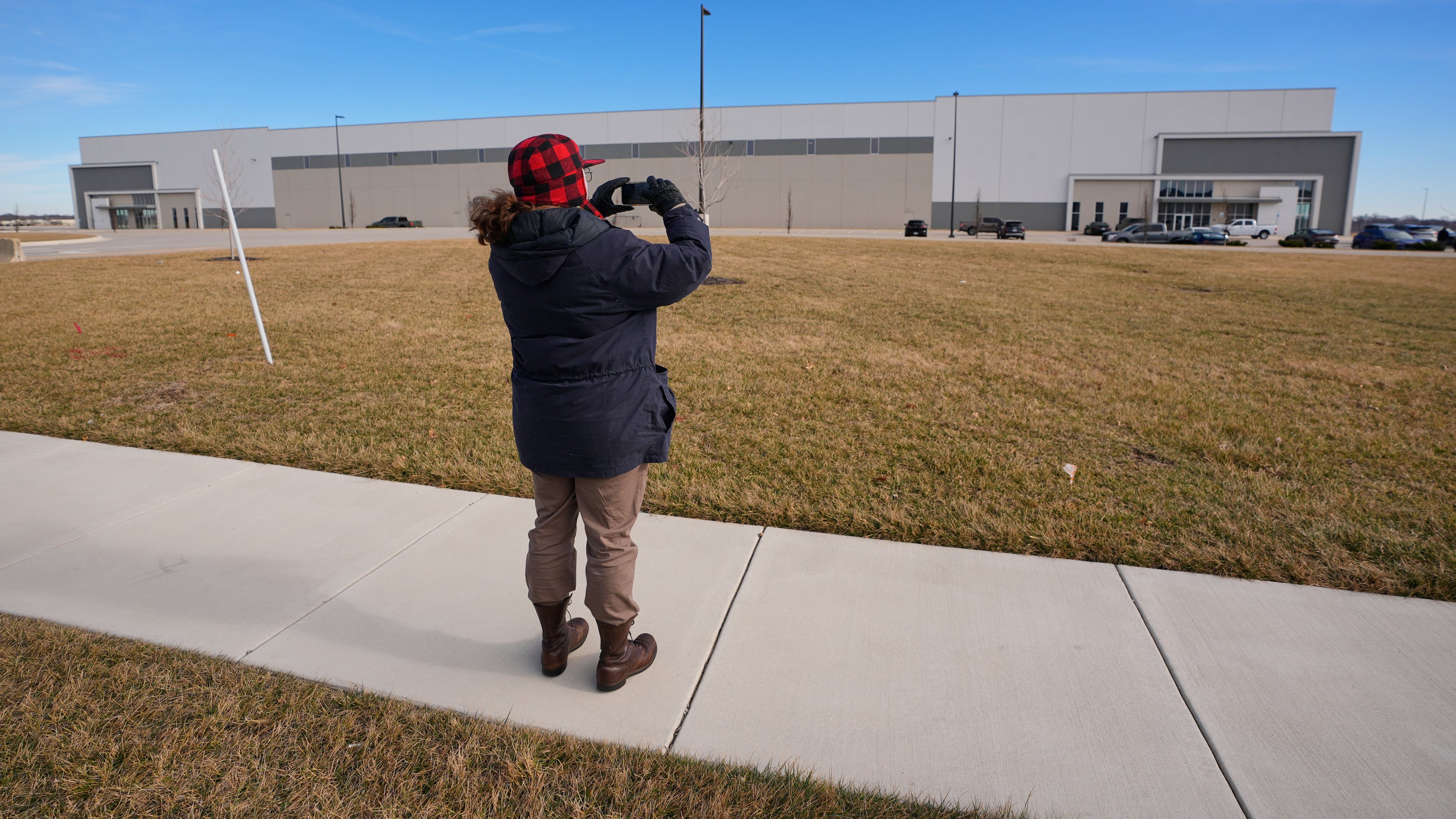 A man takes photos of a warehouse as federal officials tour the facility to consider repurposing it as an ICE detention facility Thursday, Jan. 15, 2026, in Belton, Mo. (AP Photo/Charlie Riedel)
