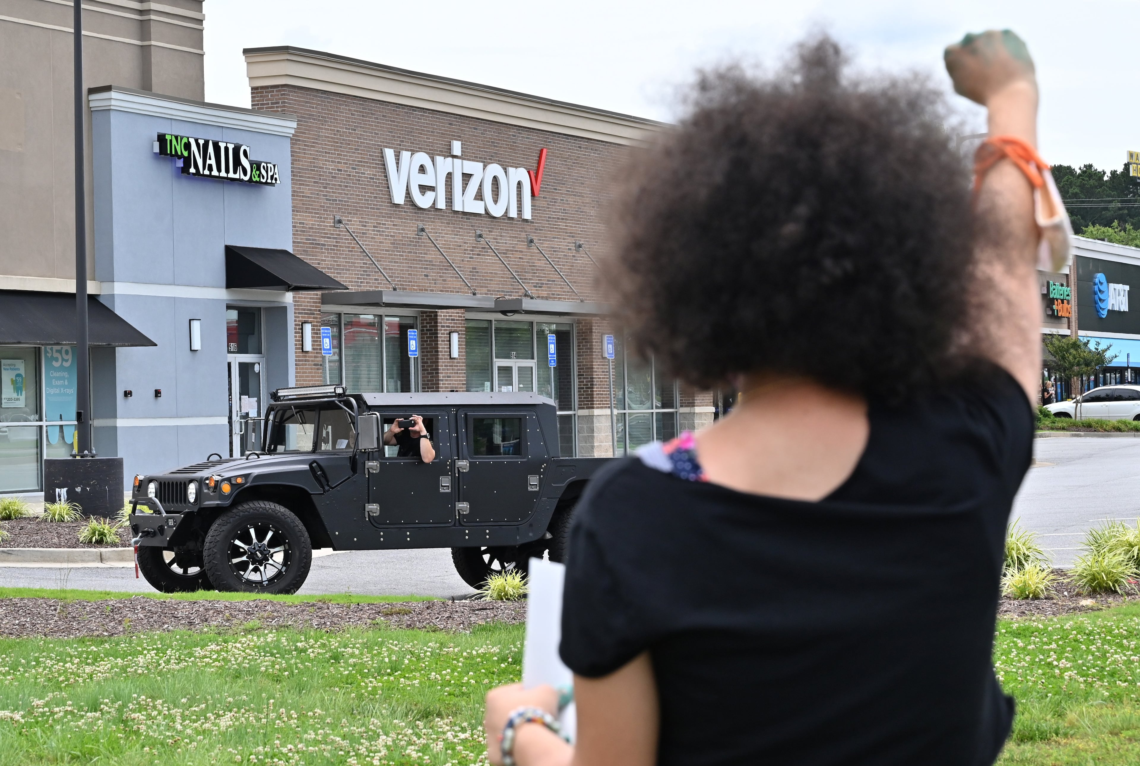 One of the teen organizers Kai Loving (foreground), 16, pumps her fist as a counter-protester takes a photograph from a distance during a protest over the death of George Floyd in Minneapolis police custody in Cummings on Saturday, June 6, 2020. Rallies are scheduled throughout the metro area Saturday, including in Cobb, Forsyth, Fayette and Gwinnett counties. (Hyosub Shin / Hyosub.Shin@ajc.com)