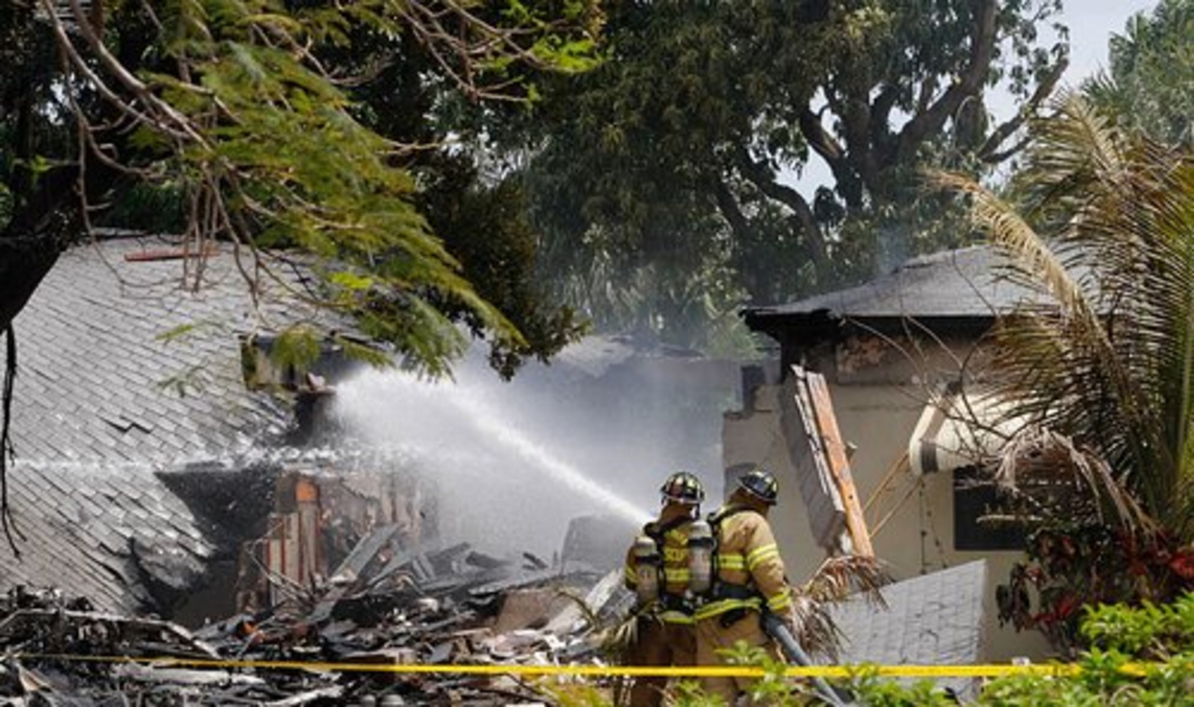 Firefighters hose down the remains of the house.