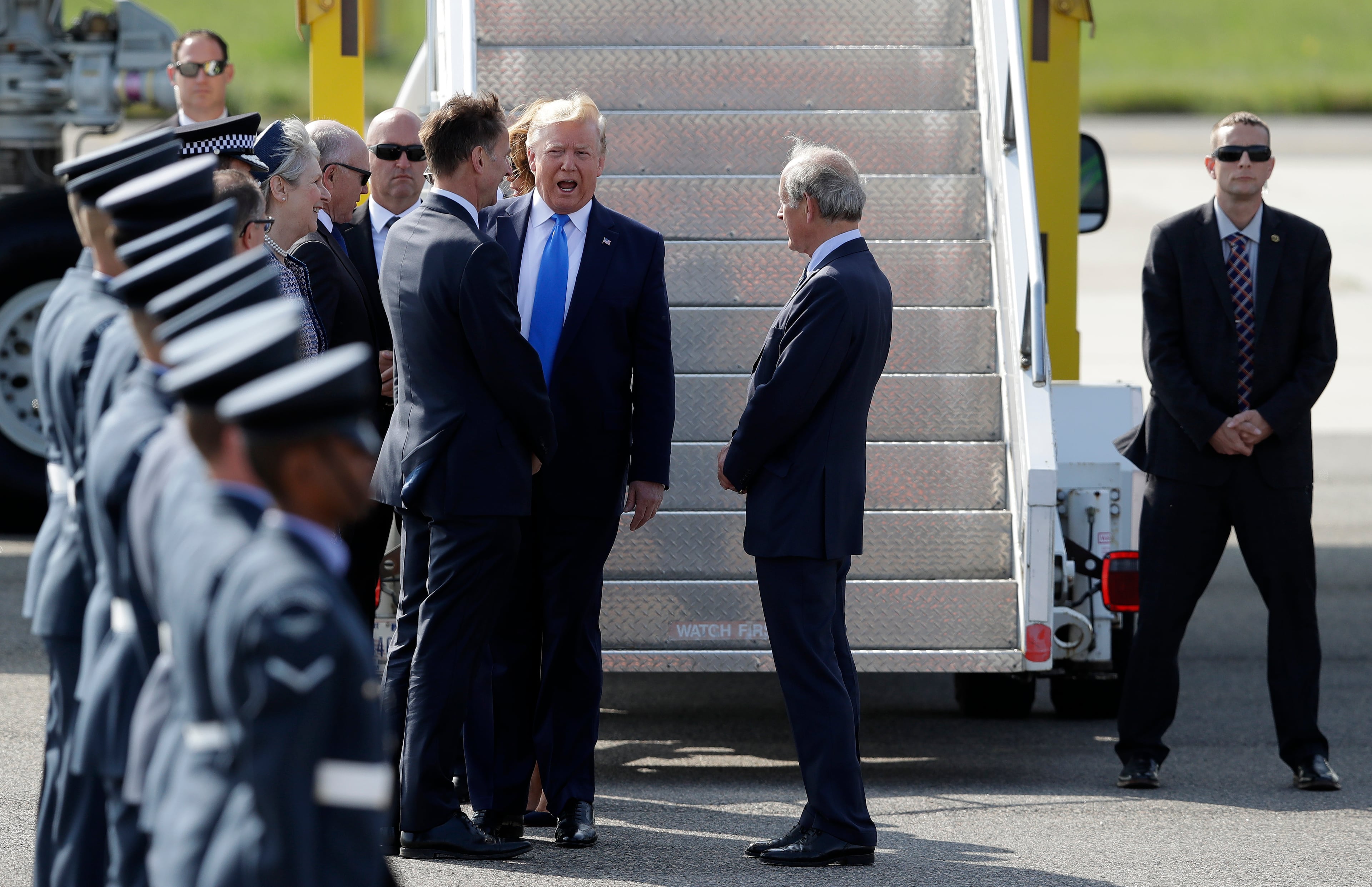 President Donald Trump by Britain's Foreign Secretary Jeremy Hunt, center left, as he arrives at Stansted Airport in England, Monday, June 3, 2019 at the start of a three day state visit to Britain. (AP Photo/Kirsty Wigglesworth)