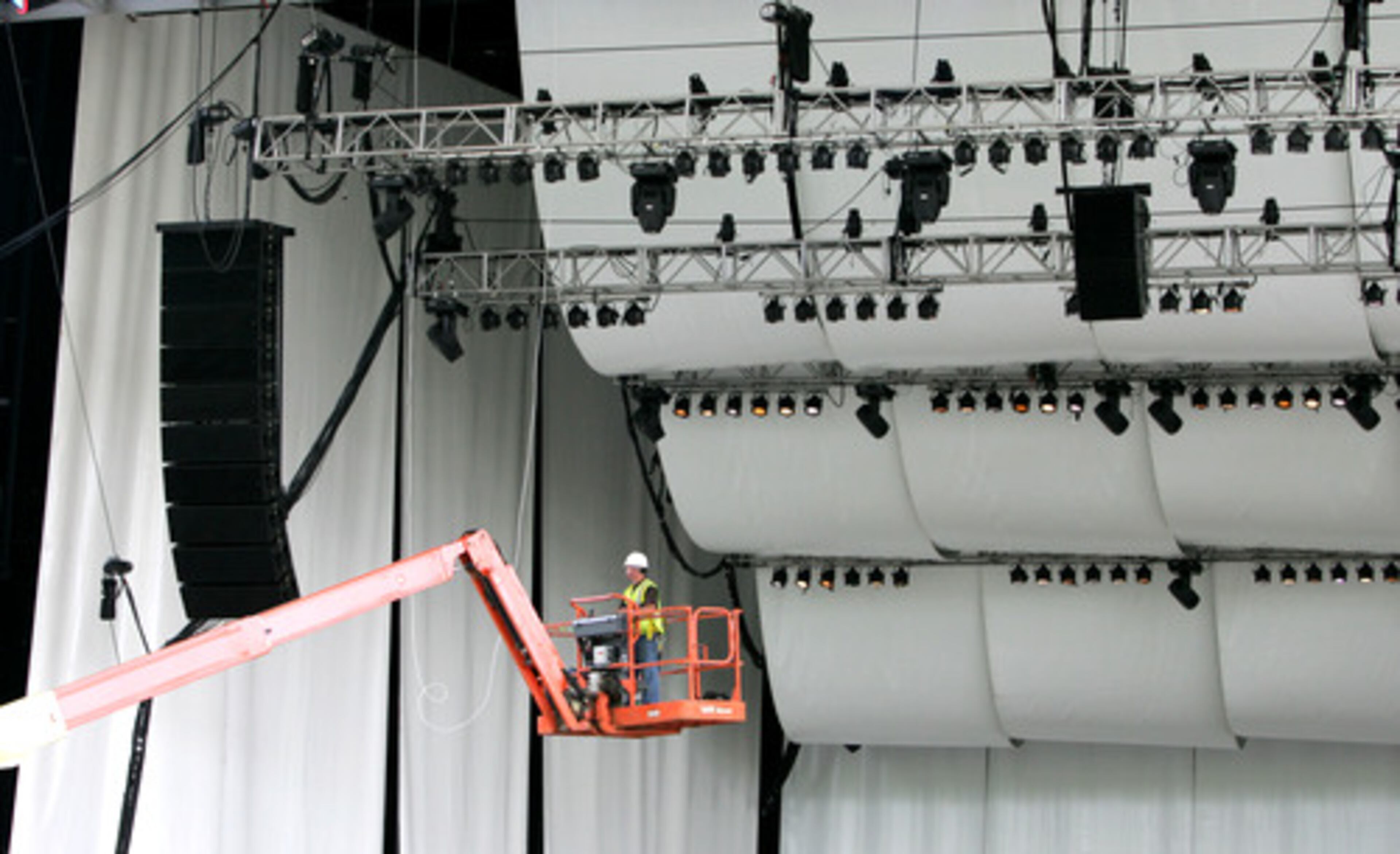 A WORKER ENSURES that all lighting and sound equipment is in place on the stage.