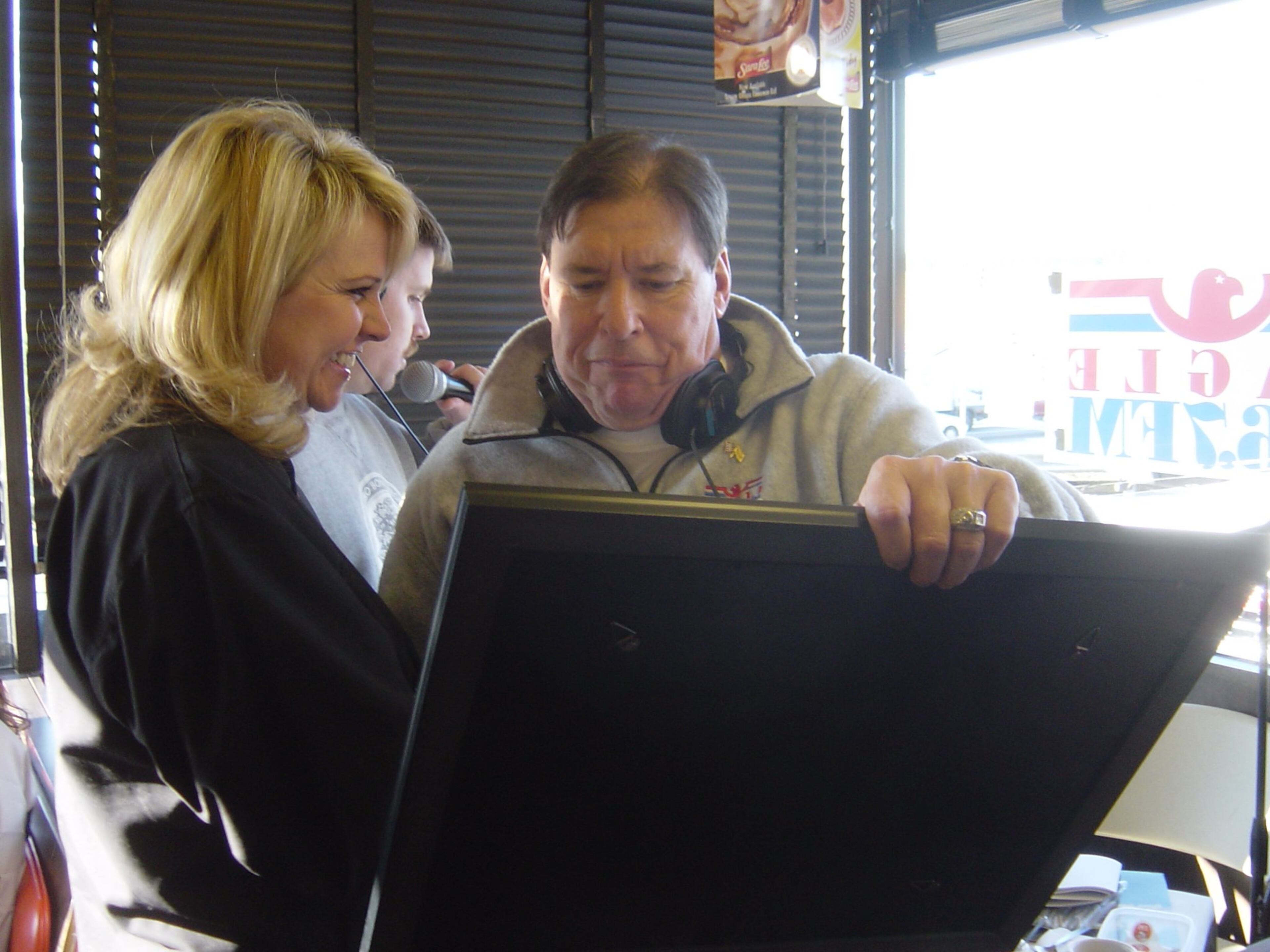 050211 KENNESAW: Warren 'Rhubarb' Jones celebrated 20 years on the air at country station Eagle 106.7 Friday morning at a Waffle House off Barrett Parkway in Kennesaw. Eagle staff gave him a matted photo of Rhubarb signed by radio employees. Dallas McCade, his sidekick, is on the left. (Rodney Ho / AJC staff)