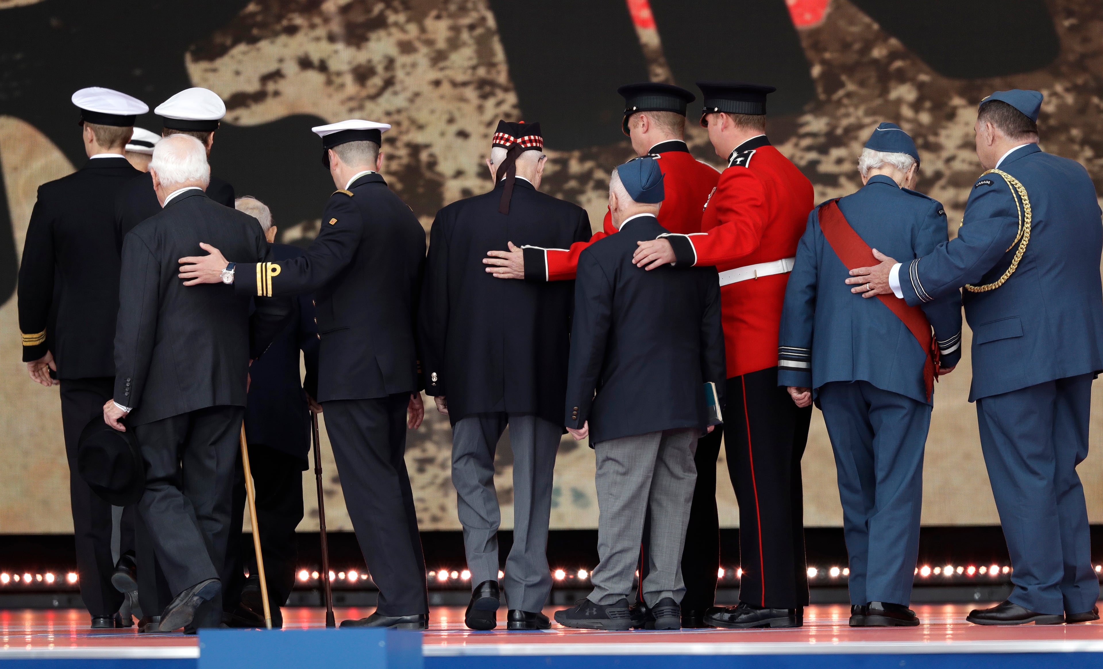 Servicemen assist D-Day veterans off stage during an event to mark the 75th anniversary of D-Day in Portsmouth, England Wednesday, June 5, 2019. World leaders including U.S. President Donald Trump are gathering Wednesday on the south coast of England to mark the 75th anniversary of the D-Day landings. (AP Photo/Matt Dunham)
