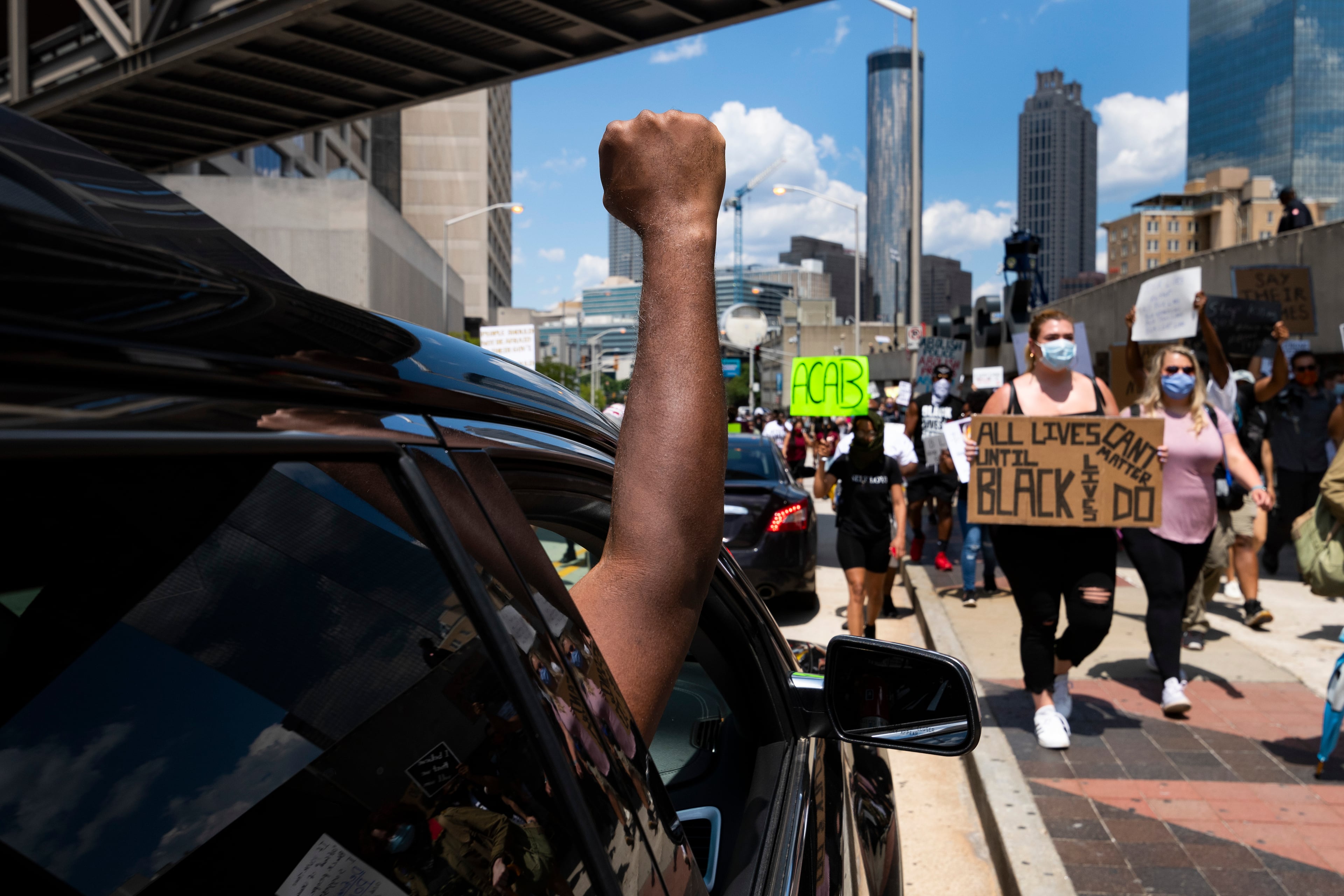 Protesters get support from a passenger of a car as they march past CNN on Saturday afternoon, June 13, 2020, during a demonstration over the Minneapolis police shooting of George Floyd, and Rayshard Brooks, a 27-year-old black man, was shot and killed by Atlanta Police on Friday evening during a struggle in a drive-thru line. JOHN AMIS FOR THE ATLANTA JOURNAL-CONSTITUTION.