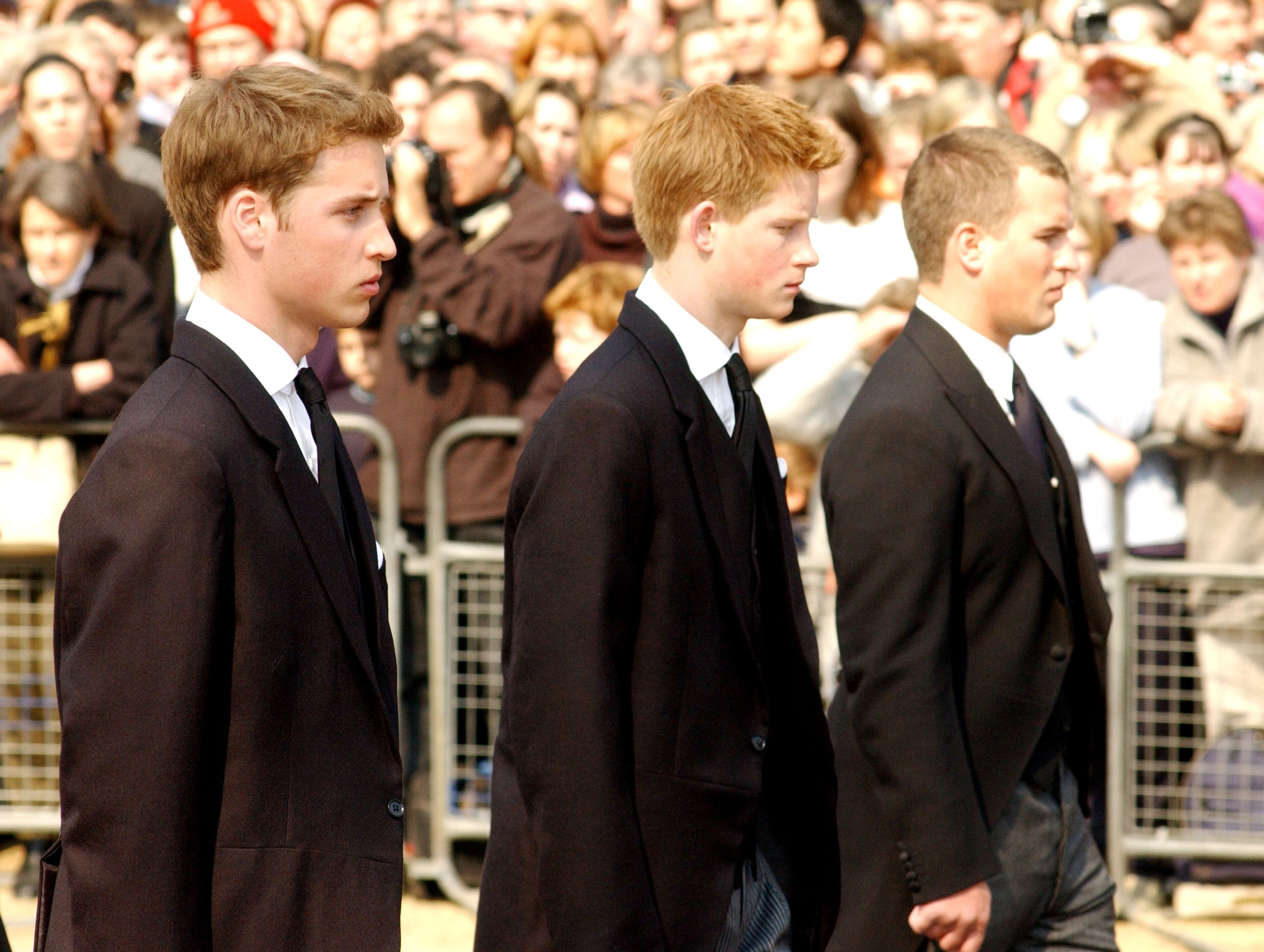 Prince William (left), Prince Harry (center) and Peter Phillips walk behind the coffin bearing the Queen Mother April 5, 2002, as her ceremonial procession makes its way down the Mall in London.