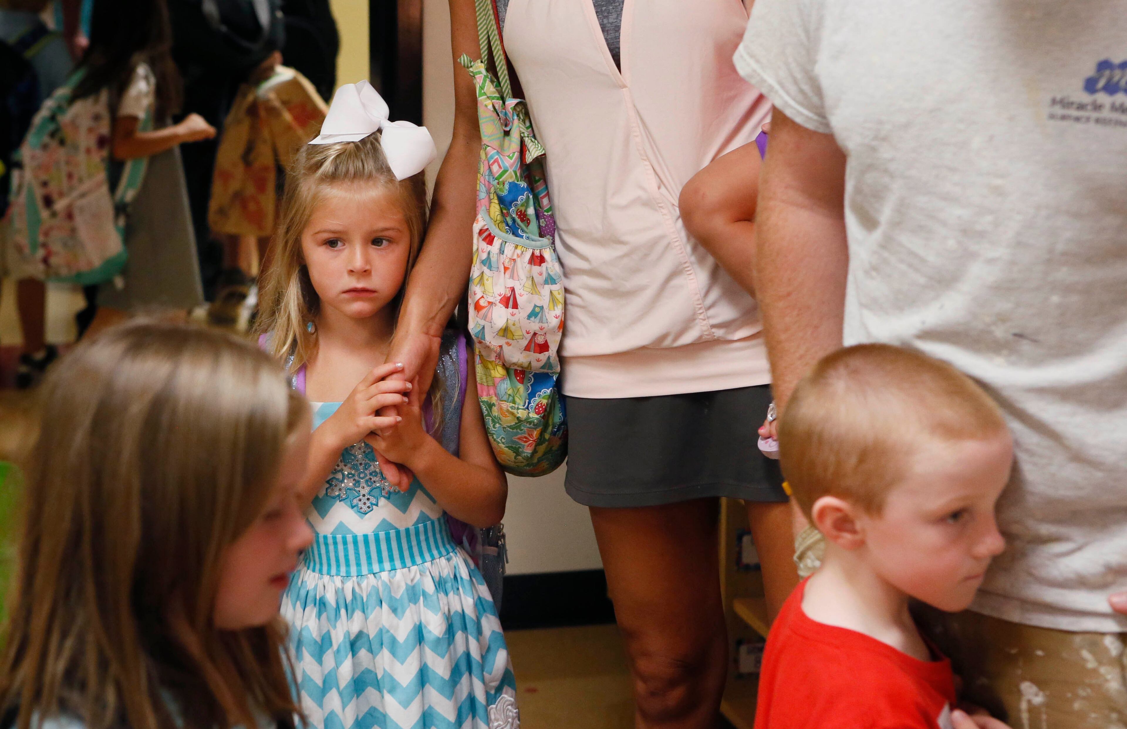Kendall Dunn gets some reassurance from her mom, Jill Dunn (left), and her kindergarten teacher, Kelley Laukes. On the first day of school at Birmingham Falls Elementary in Milton new kindergarten students and their parents arrive at their new classroom. BOB ANDRES / BANDRES@AJC.COM