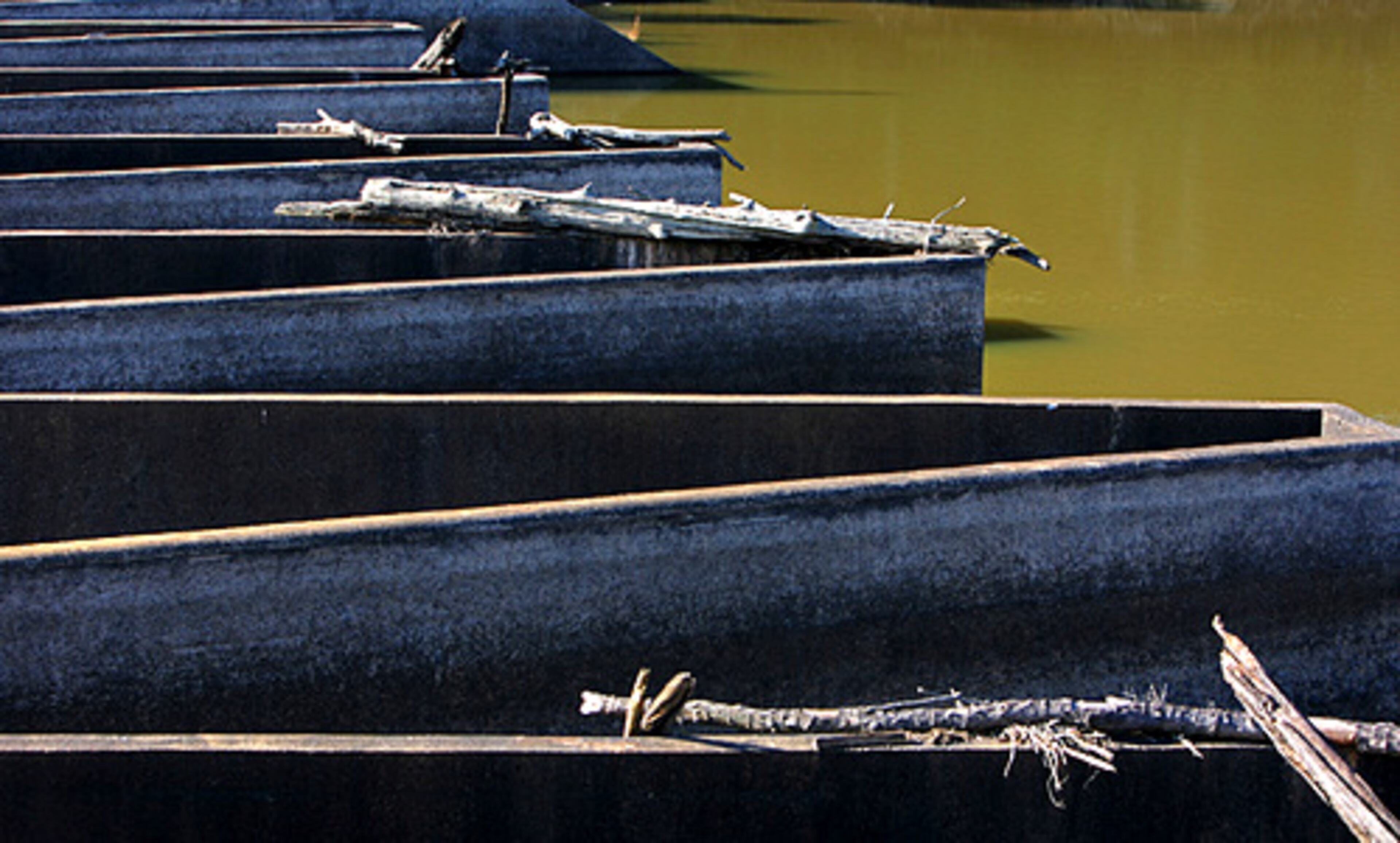 The dock for sightseeing and fishing at the reservoir lies twisted in a crazy angle on the muddy banks.