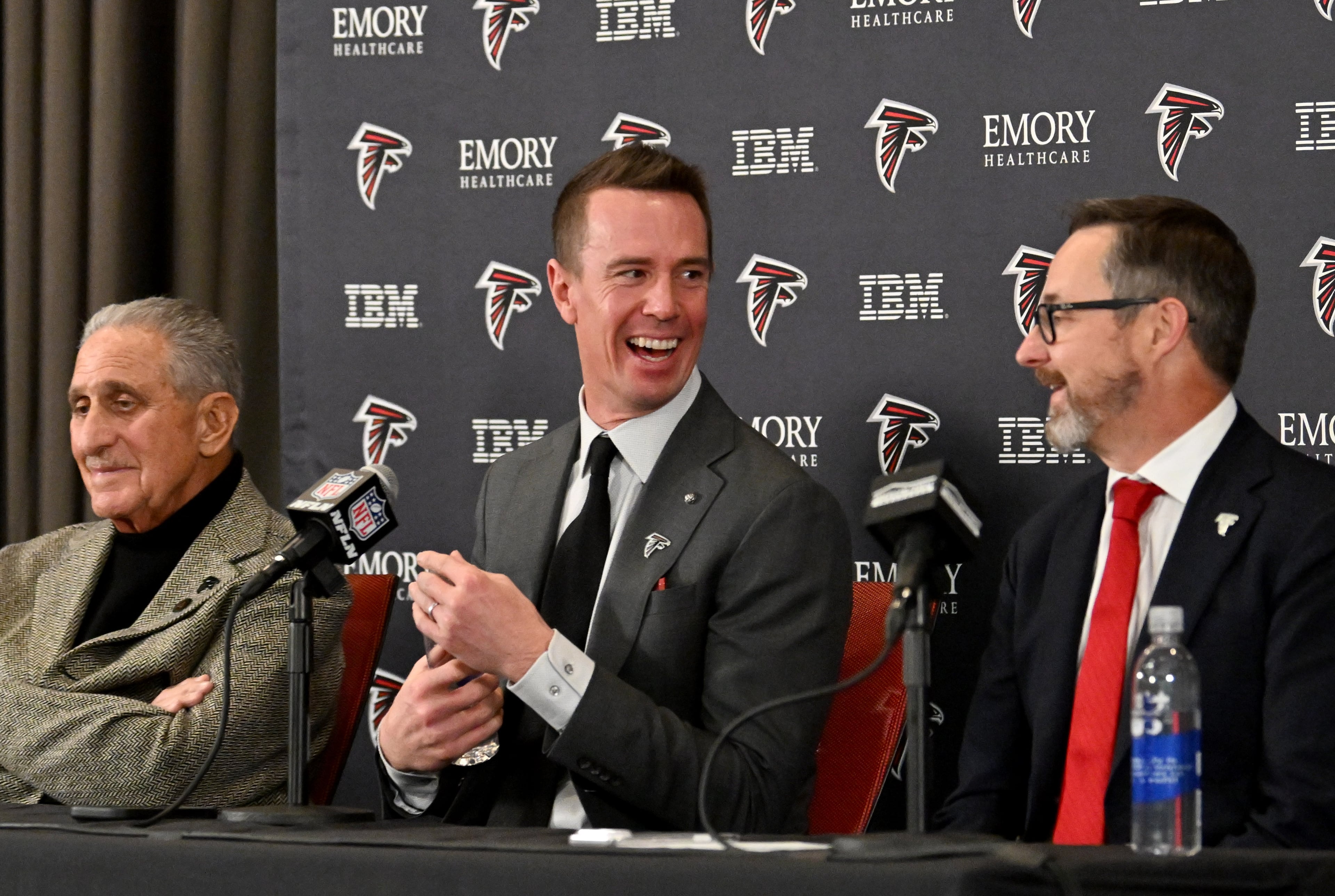 New Falcons president of football Matt Ryan reacts as Arthur M. Blank (left) and CEO Greg Beadles sit next him during a news conference to introduce new Falcons president of football Matt Ryan, Tuesday, Jan. 13, 2026, in Flowery Branch. (Hyosub Shin/AJC)