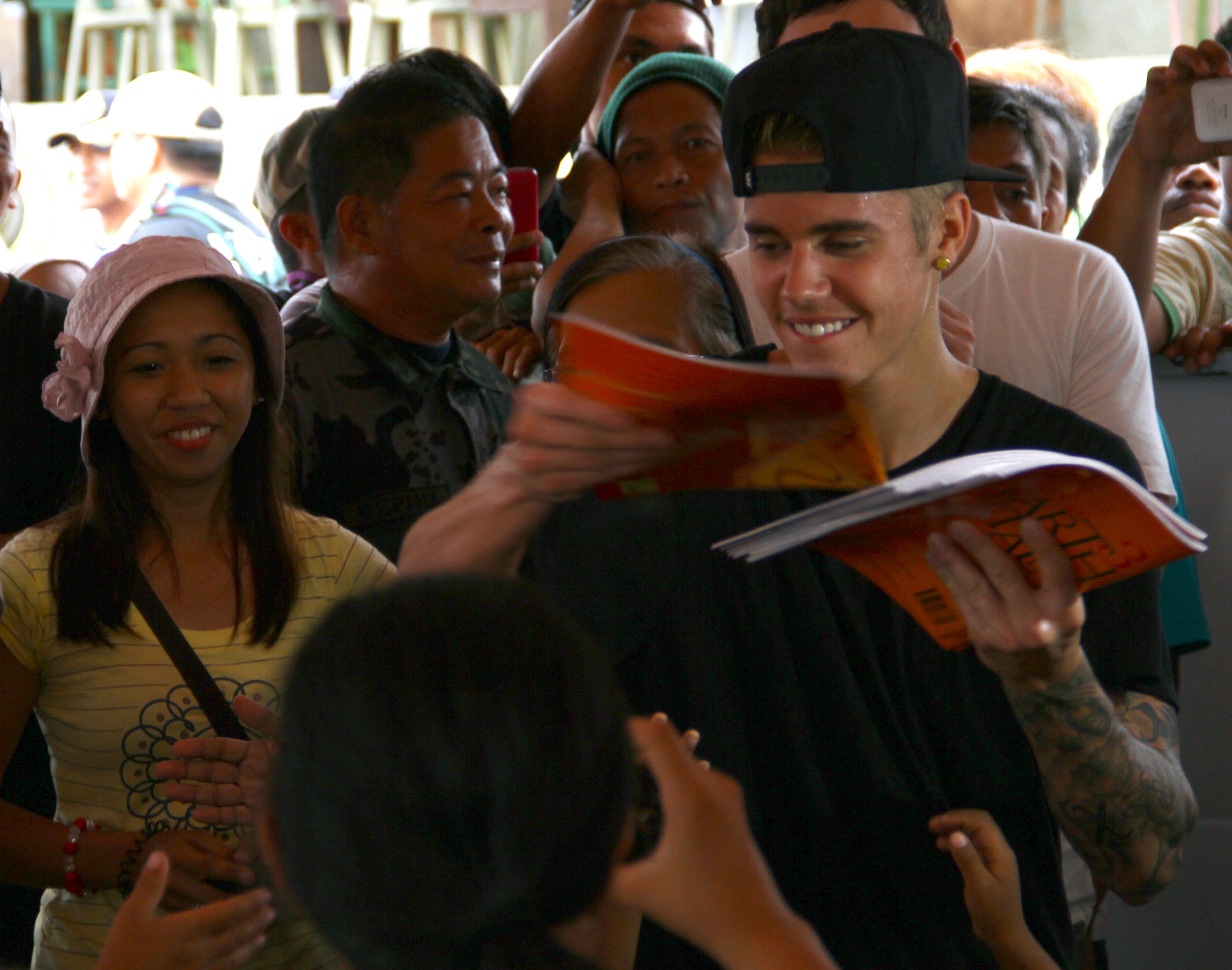 Justin Bieber prepares to sign his autographs after playing basketball with children survivors of Typhoon Haiyan during his visit to Tacloban city, Leyte province in central Philippines, Tuesday, Dec. 10, 2013. The teen heartthrob Bieber arrived Tuesday in the Philippines, where he has launched a campaign to help victims of last month's killer typhoon. (AP Photo)