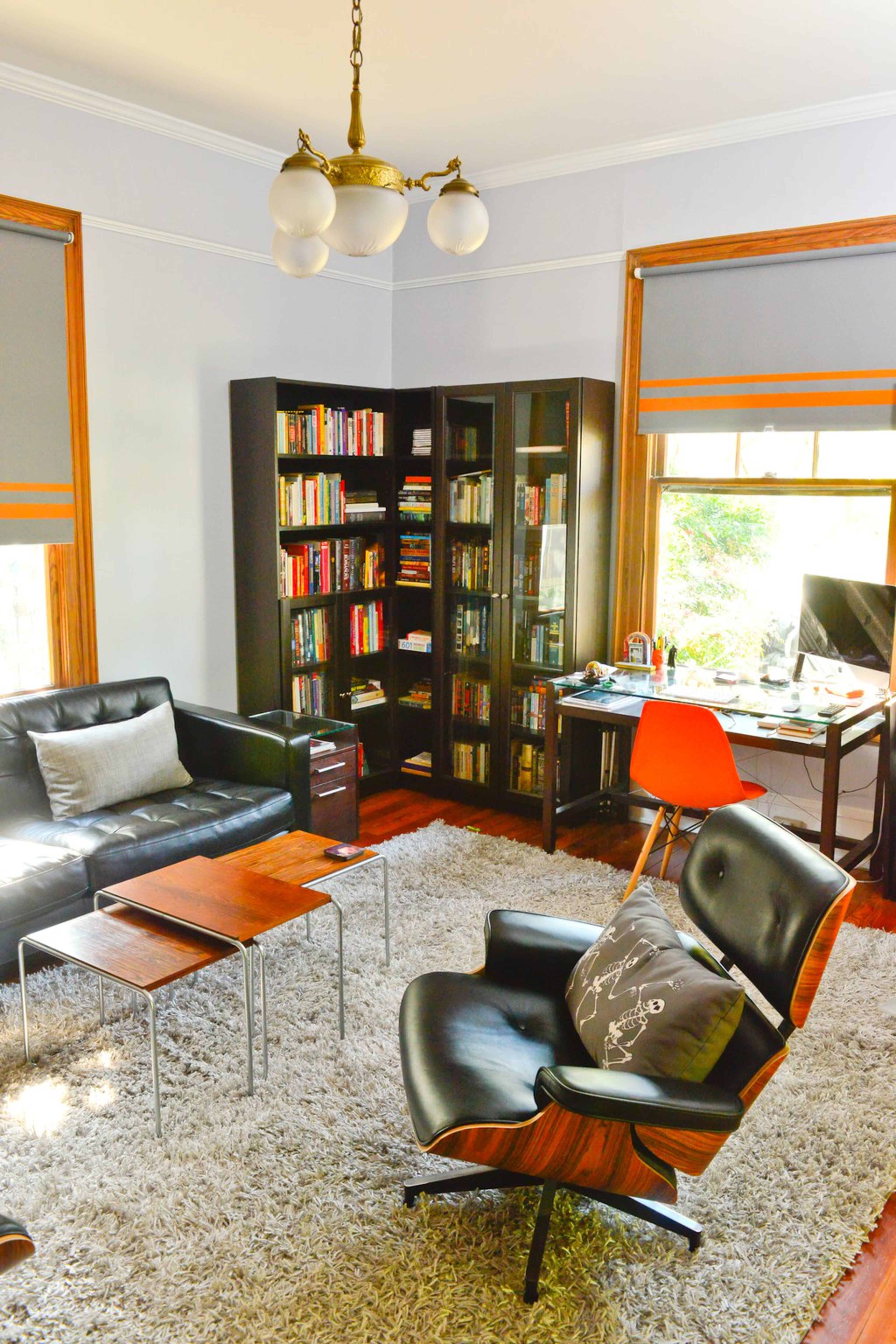 In the study, the chair is an Eames reproduction from ModwayFurniture.com. The black leather sofa is from IKEA and the nesting tables are from City Issue. For the drapes, the homeowners used fabric from IKEA and added the stripes.