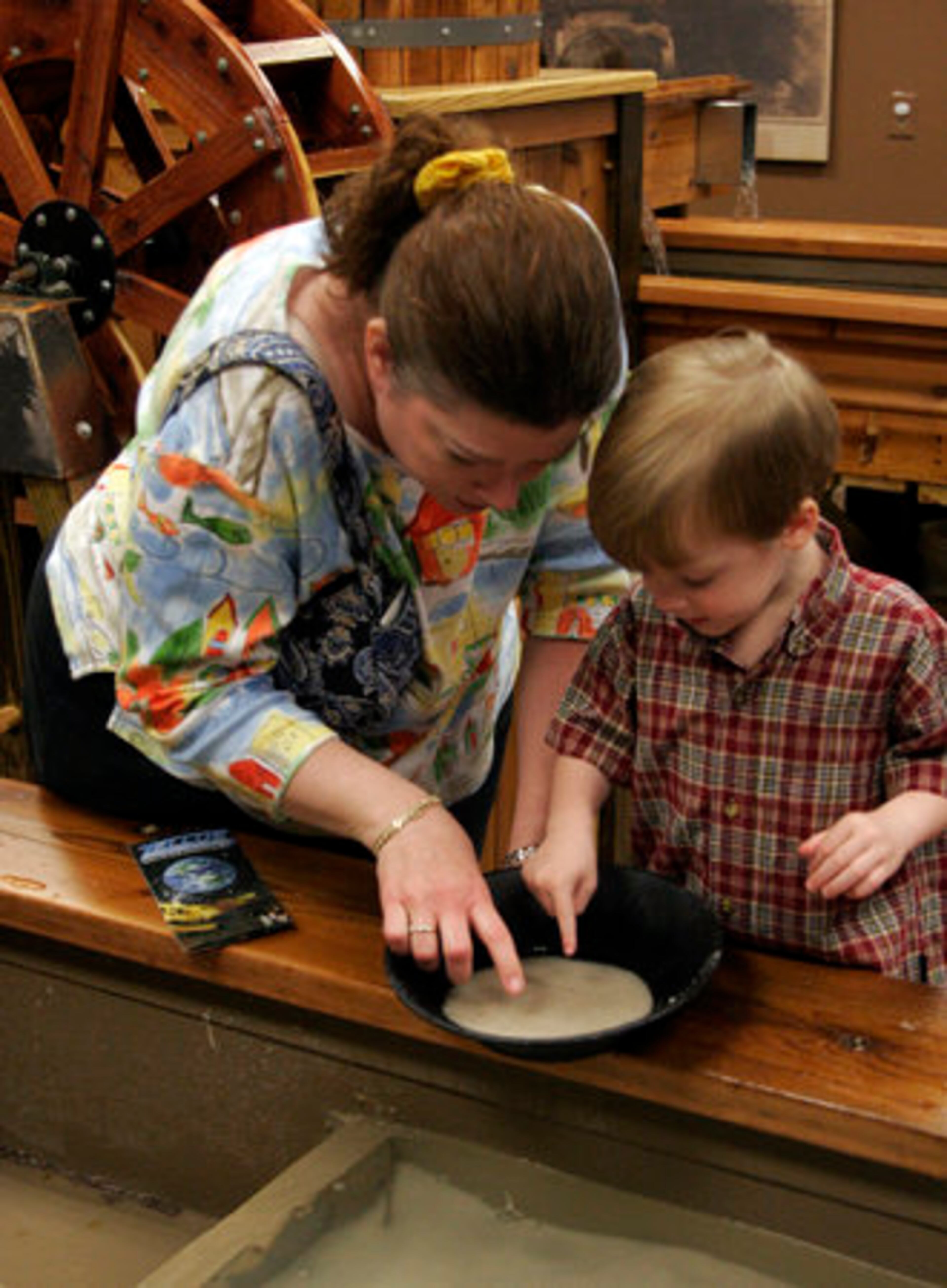 ALANNA YOUNG and her 3-year-old son, Coleman, pan for gems in an interactive exhibit.