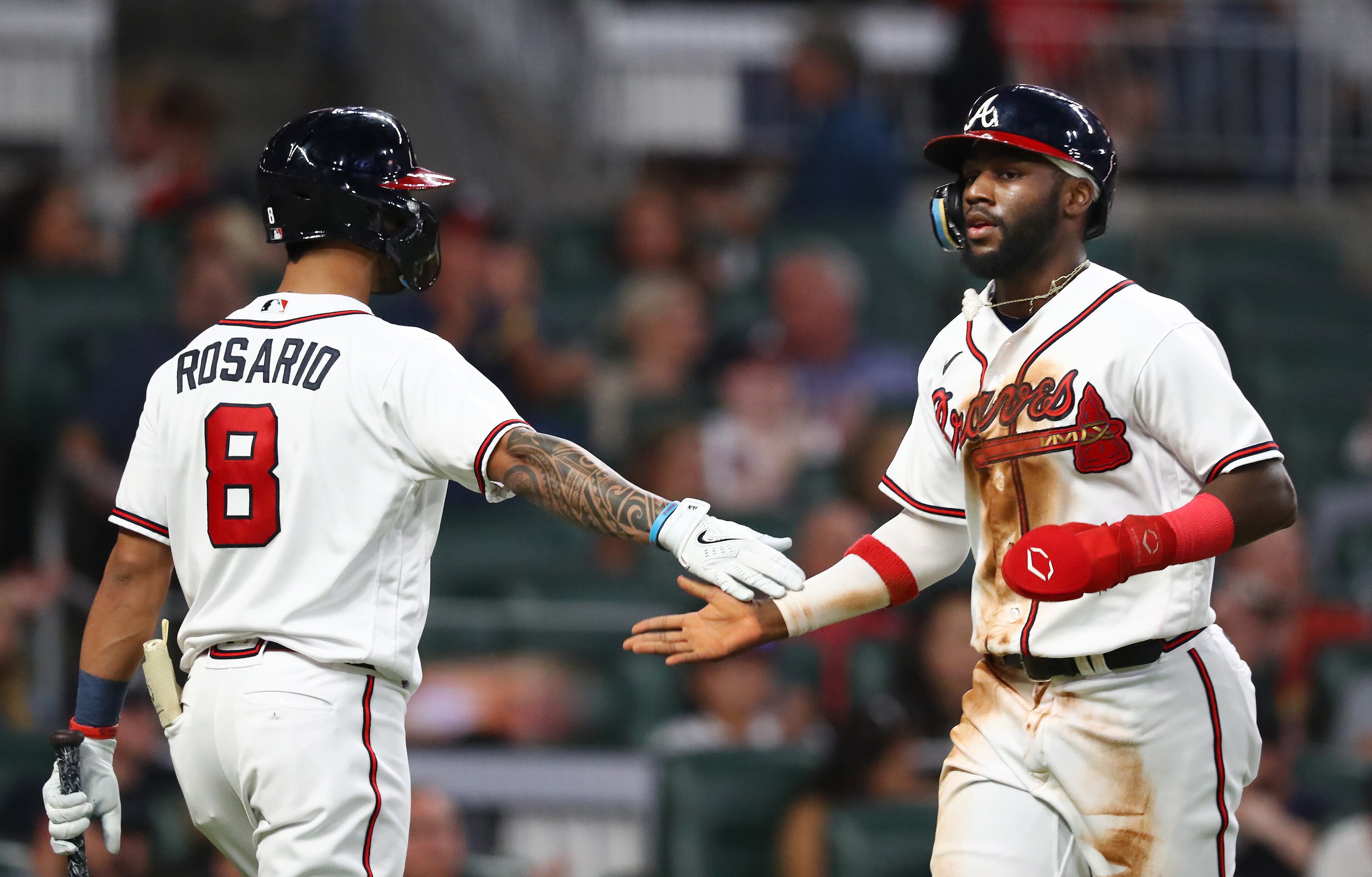 Braves outfielder Michael Harris (right) gets five from Eddie Rosario after Harris scored on William Contreras' sacrifice fly Monday night at Truist Park. (Curtis Compton / Curtis Compton@ajc.com)