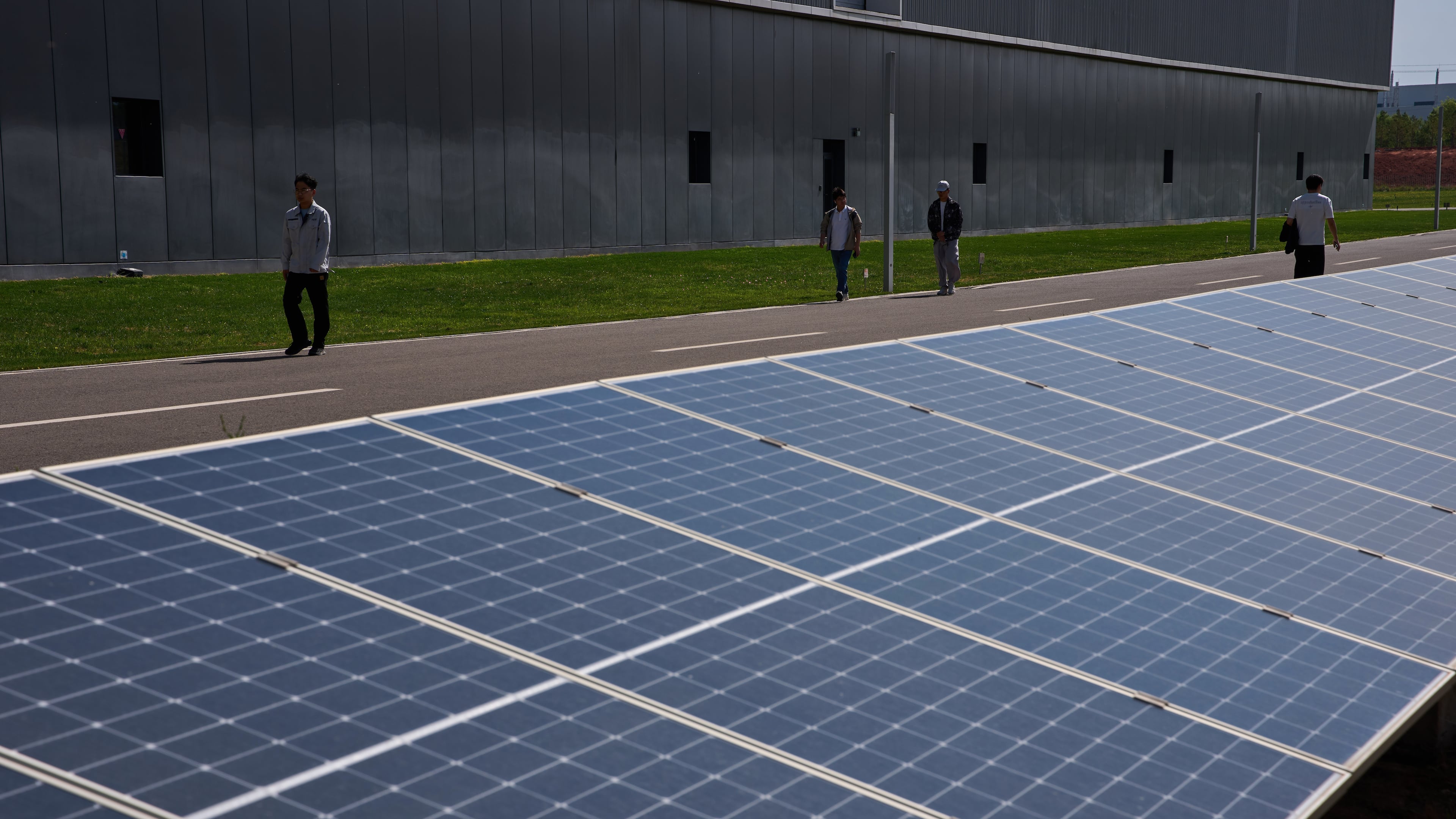Workers walk by solar panels in the Envision Ordos Modern Energy Equipment Industrial Park in Ordos in northern China's Inner Mongolia province on Friday, June 12, 2026. (AP Photo/Ng Han Guan)