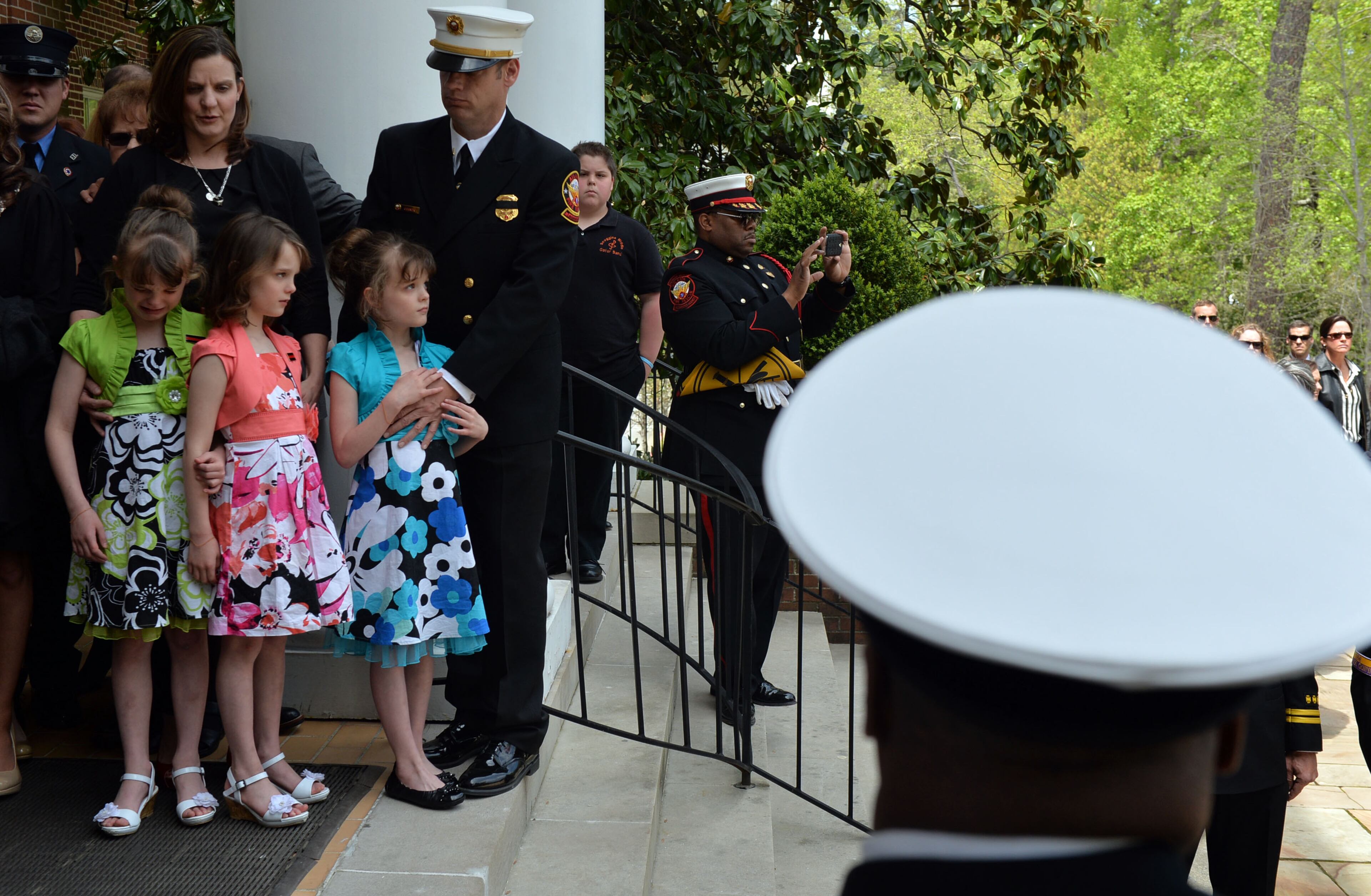 Sgt. Guinn's widow, Kimberly, stands with their 7-year-old triplets, Isabelle, Alyssa, and Makenna as the casket enters the church. Atlanta Fire Rescue officials and firefighters joined with family and friends during the funeral of AFR Sgt. Frank Guinn at Peachtree Road Presbyterian Church, Thursday, April 17, 2014.