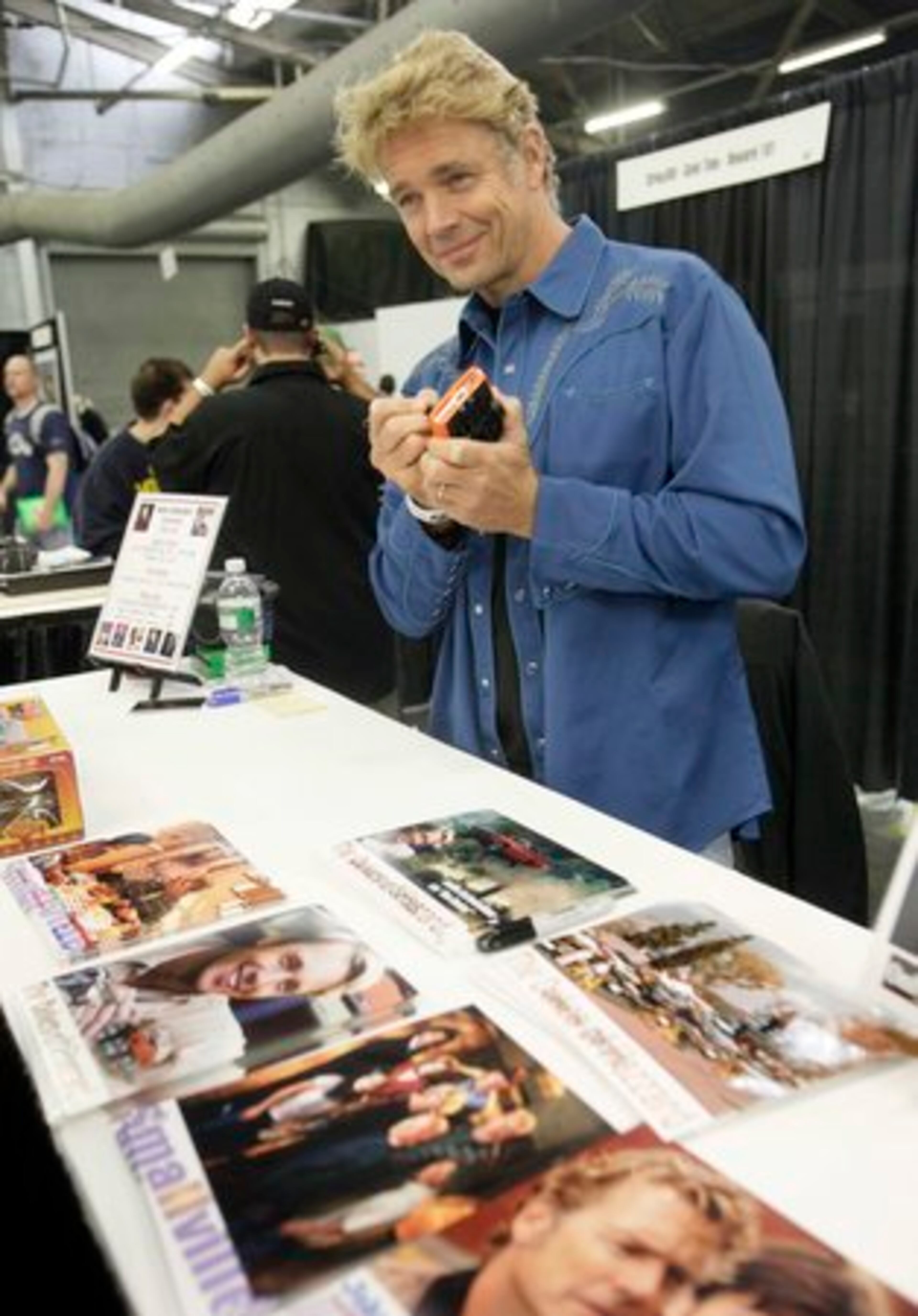 Actor John Schneider, from television's "Duke Of Hazard, " autographs a replica of the show's "General Lee" car.