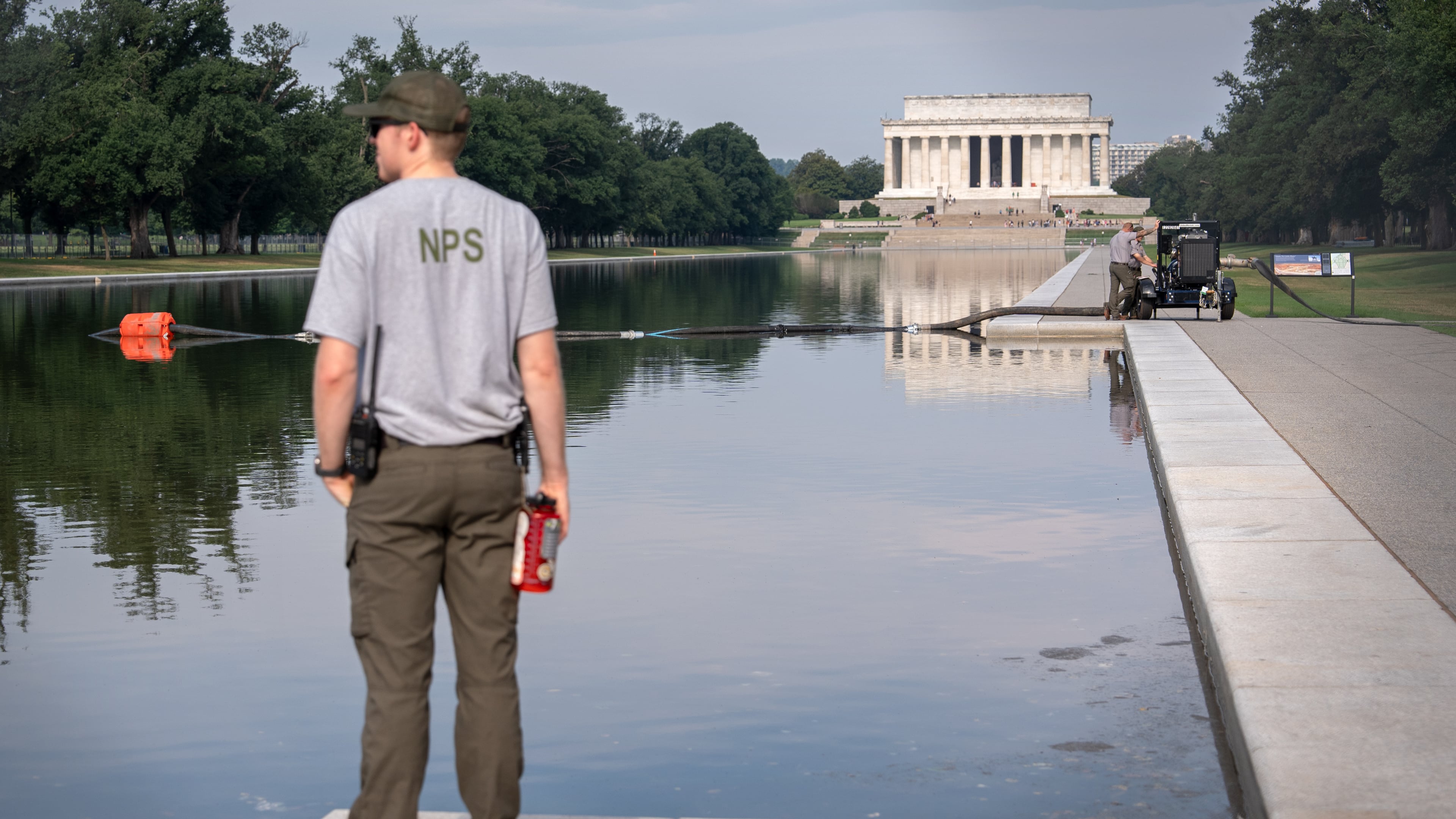 FILE - A National Park Service worker stands near a pump placed next to the Lincoln Memorial Reflecting Pool in Washington, July 10, 2026. (AP Photo/Mark Schiefelbein, File)