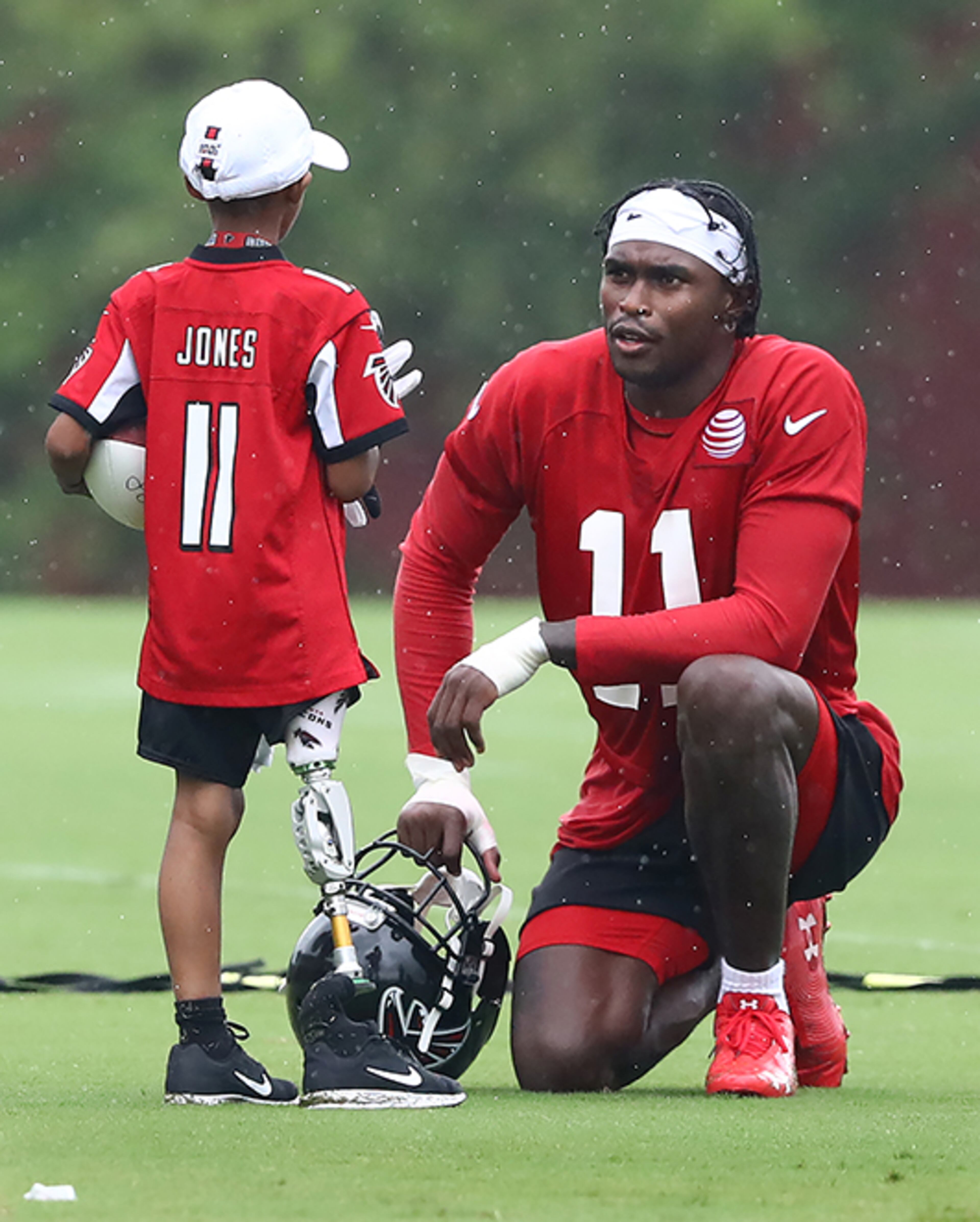 Falcons wide receiver Julio Jones pauses to spend some time with 10-year-old amputee D'Eric Salder after the second practice of training camp Tuesday, July 23, 2019, in Flowery Branch.